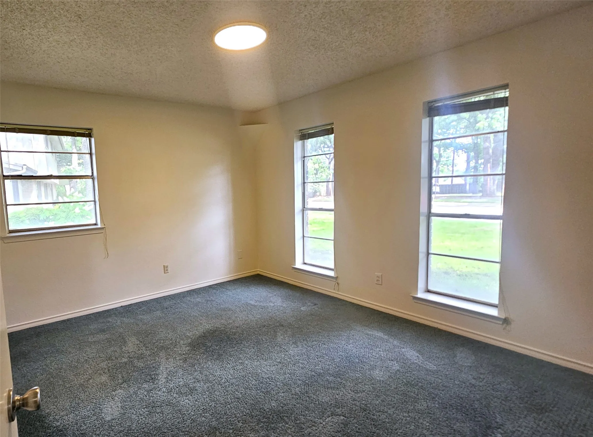Bedroom 6 with views of front and side of the house. Blue carpet, and baseboards
