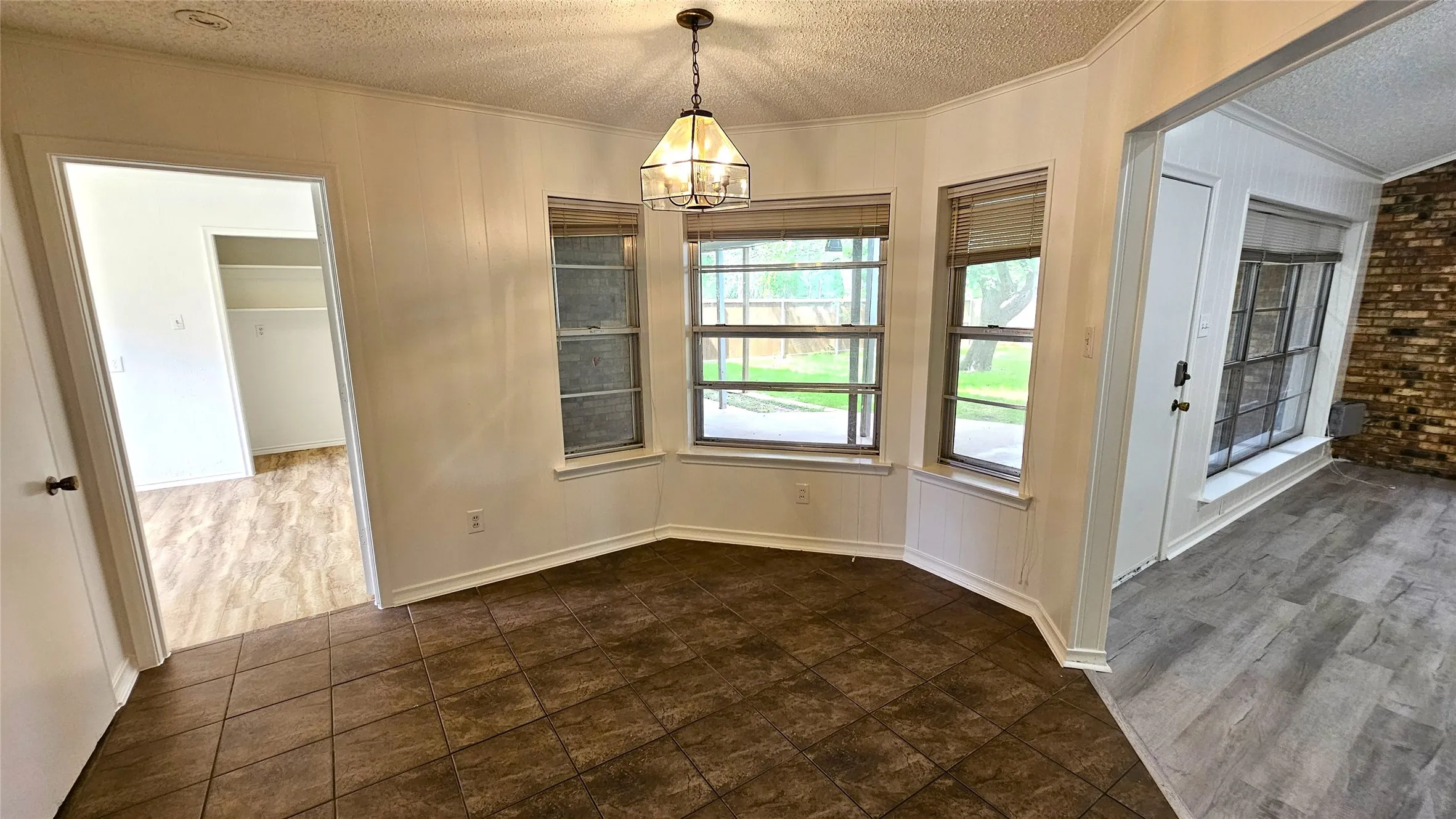 Dining area with a textured ceiling, ornamental molding, and a chandelier with view of back yard.