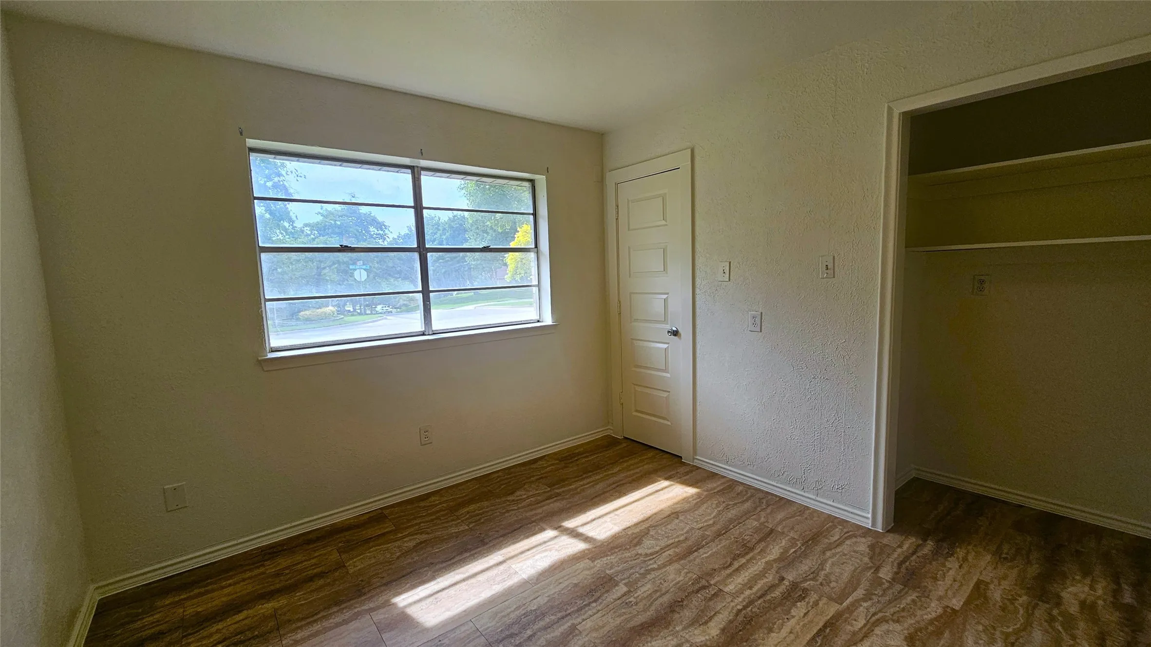 Bedroom 4 featuring luxury vinyl tyle floors, window view of side yard and ensuite full bathroom and direct access to back yard.