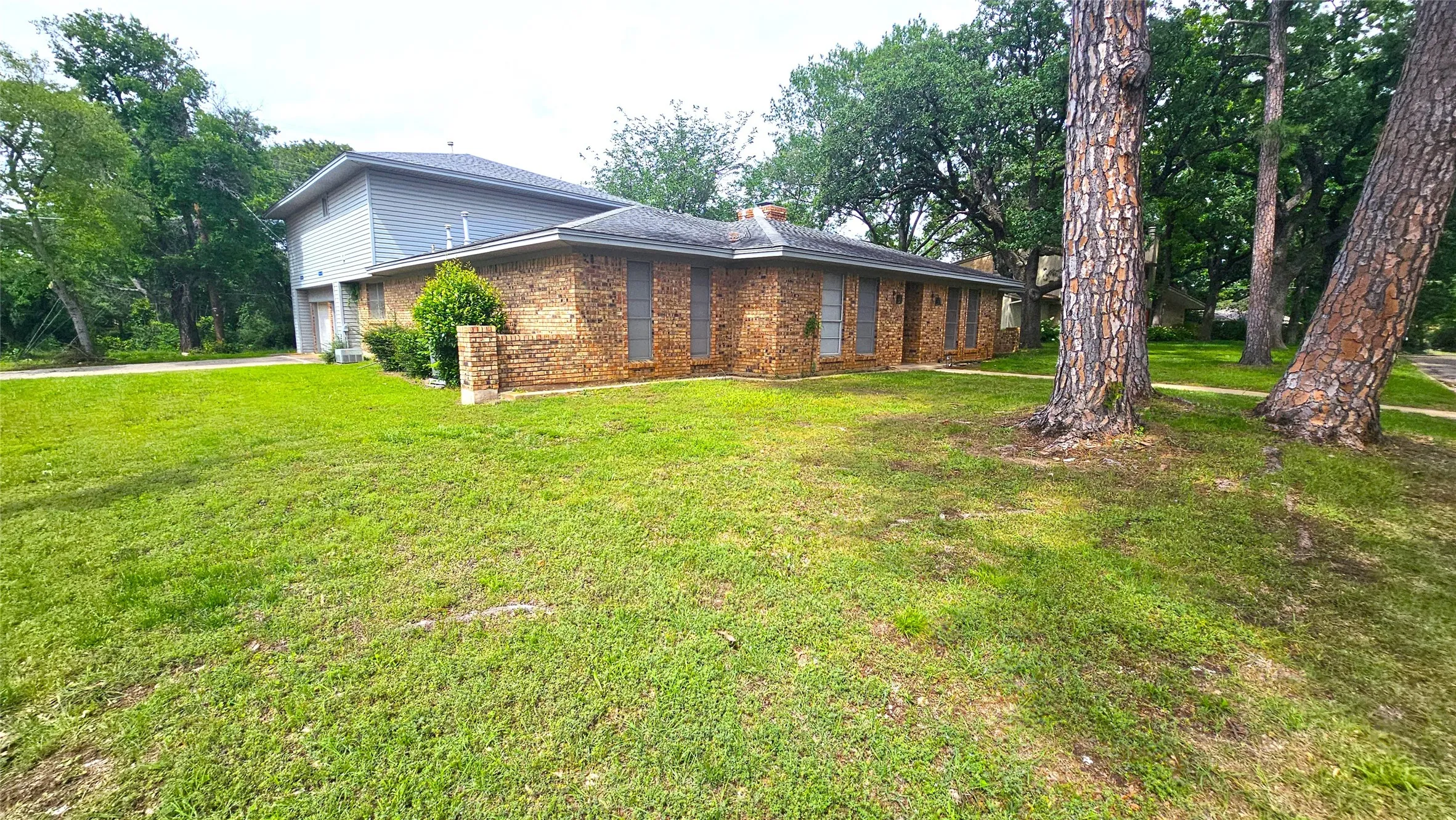 View of side of property featuring brick siding, a garage, a lawn, and a chimney