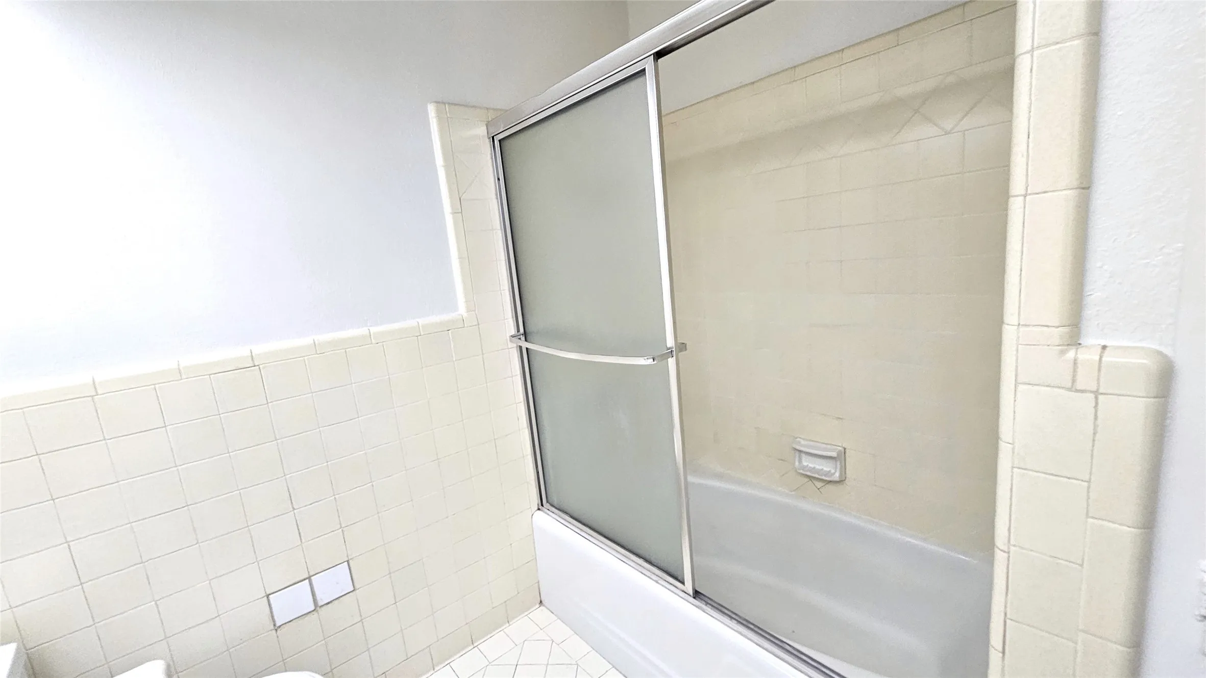 Full bath with shower / bath combination with glass door and tile walls