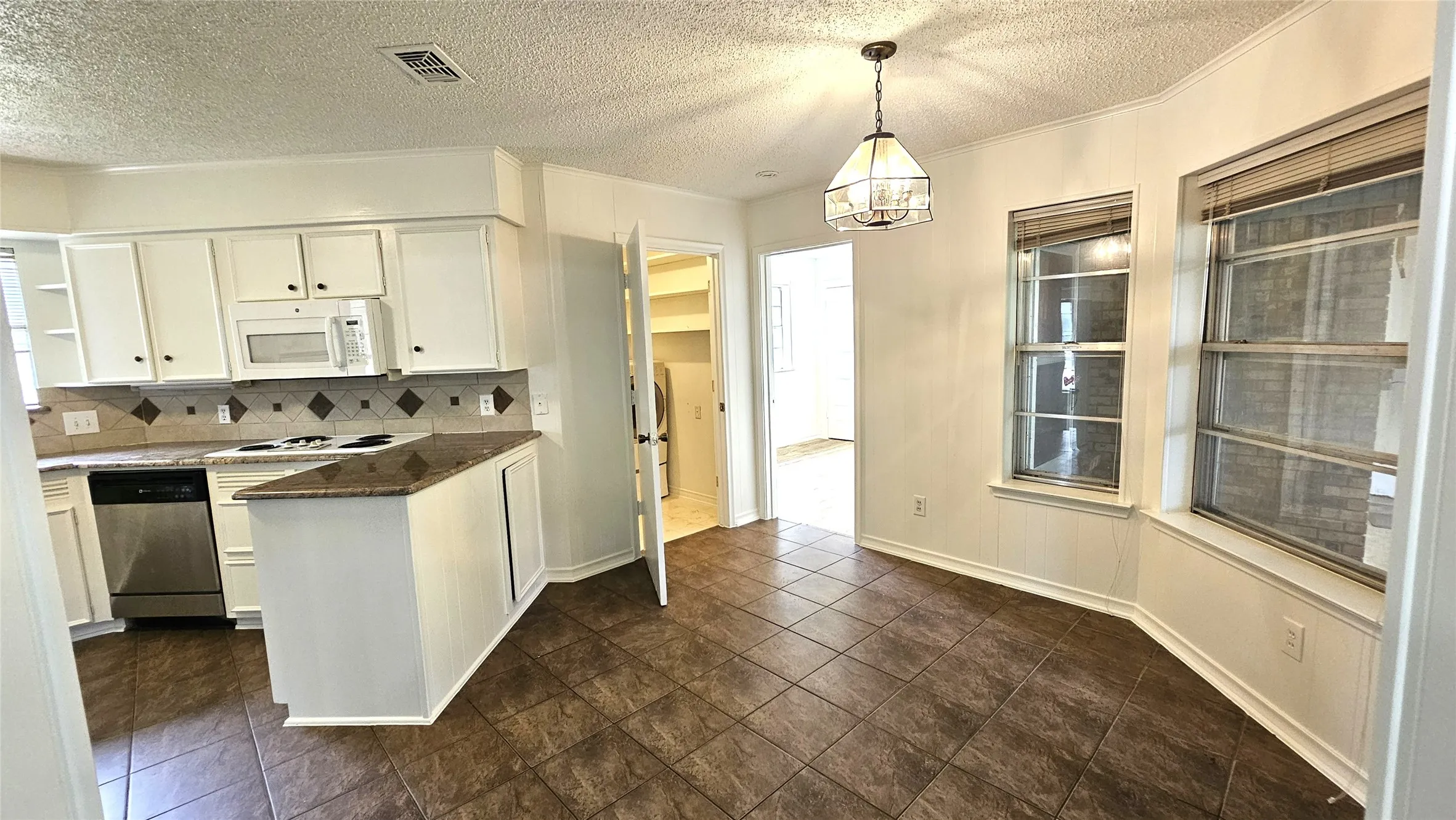 Kitchen with white appliances, white cabinets, backsplash, Granite countertops, and a peninsula