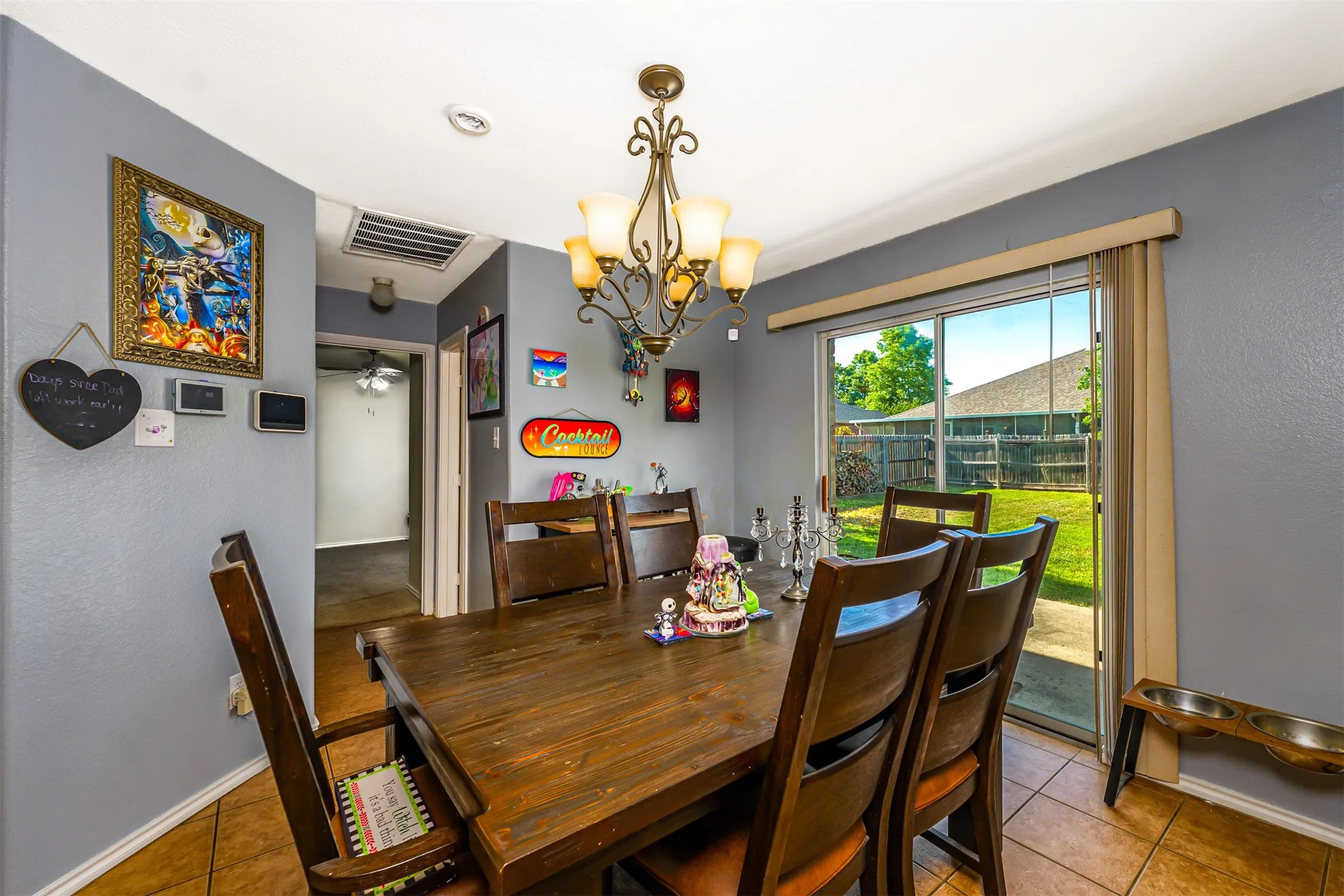 Dining area featuring tile flooring, a brass-toned chandelier, and a sliding glass door leading to the backyard