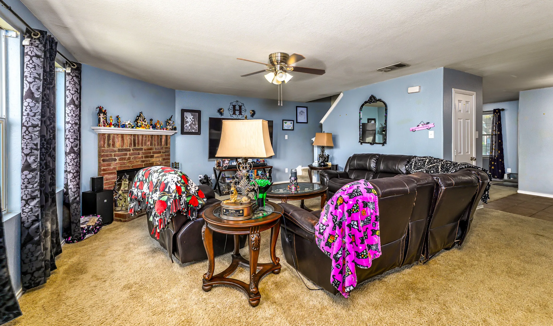 Living area featuring a brick fireplace with a white mantle, a ceiling fan, and carpet flooring