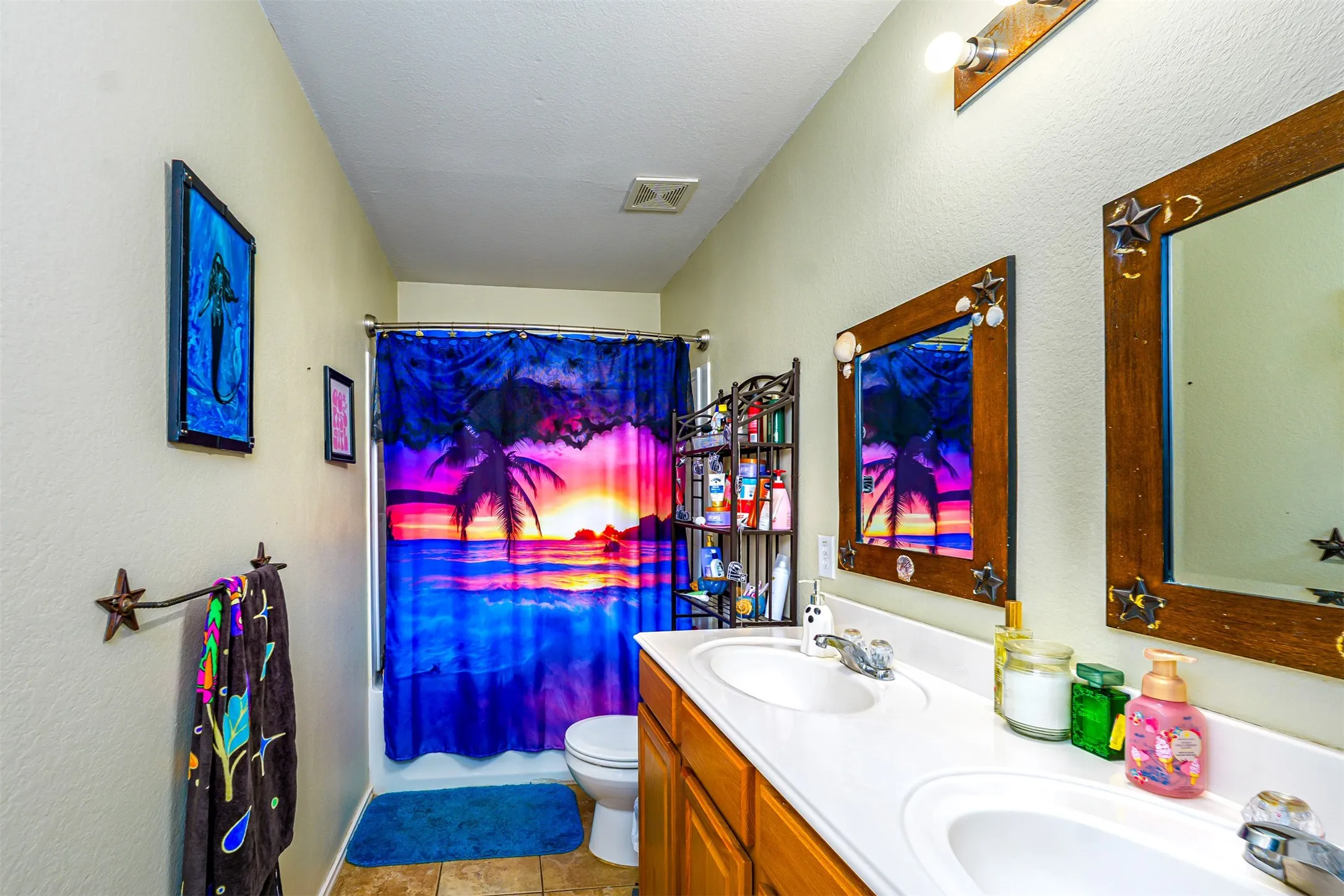 Bathroom featuring a dual vanity with integrated sinks, wood-finish cabinetry, and framed mirrors