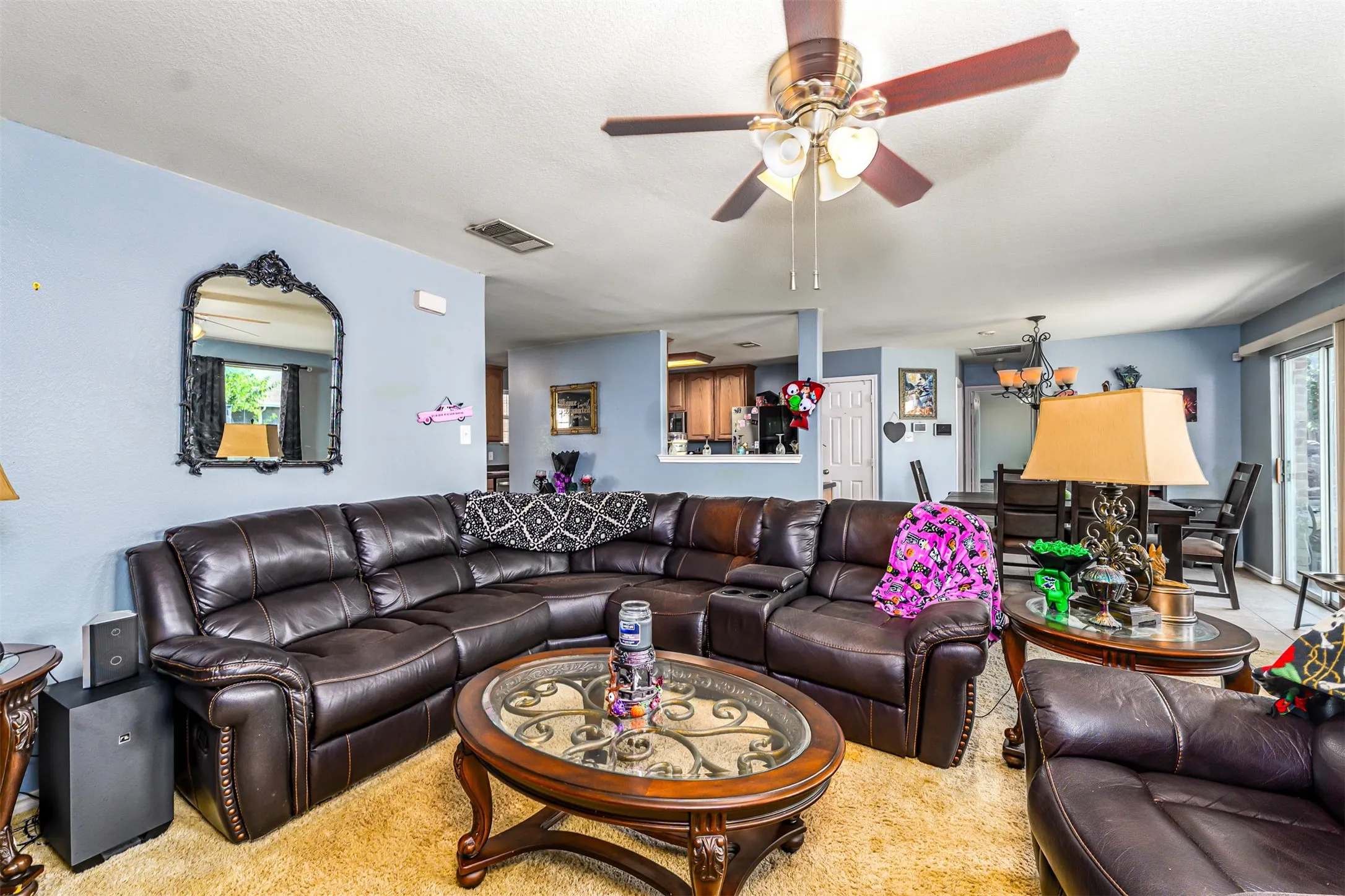 Open-concept living area with a ceiling fan, recessed lighting, and a pass-through opening to the kitchen