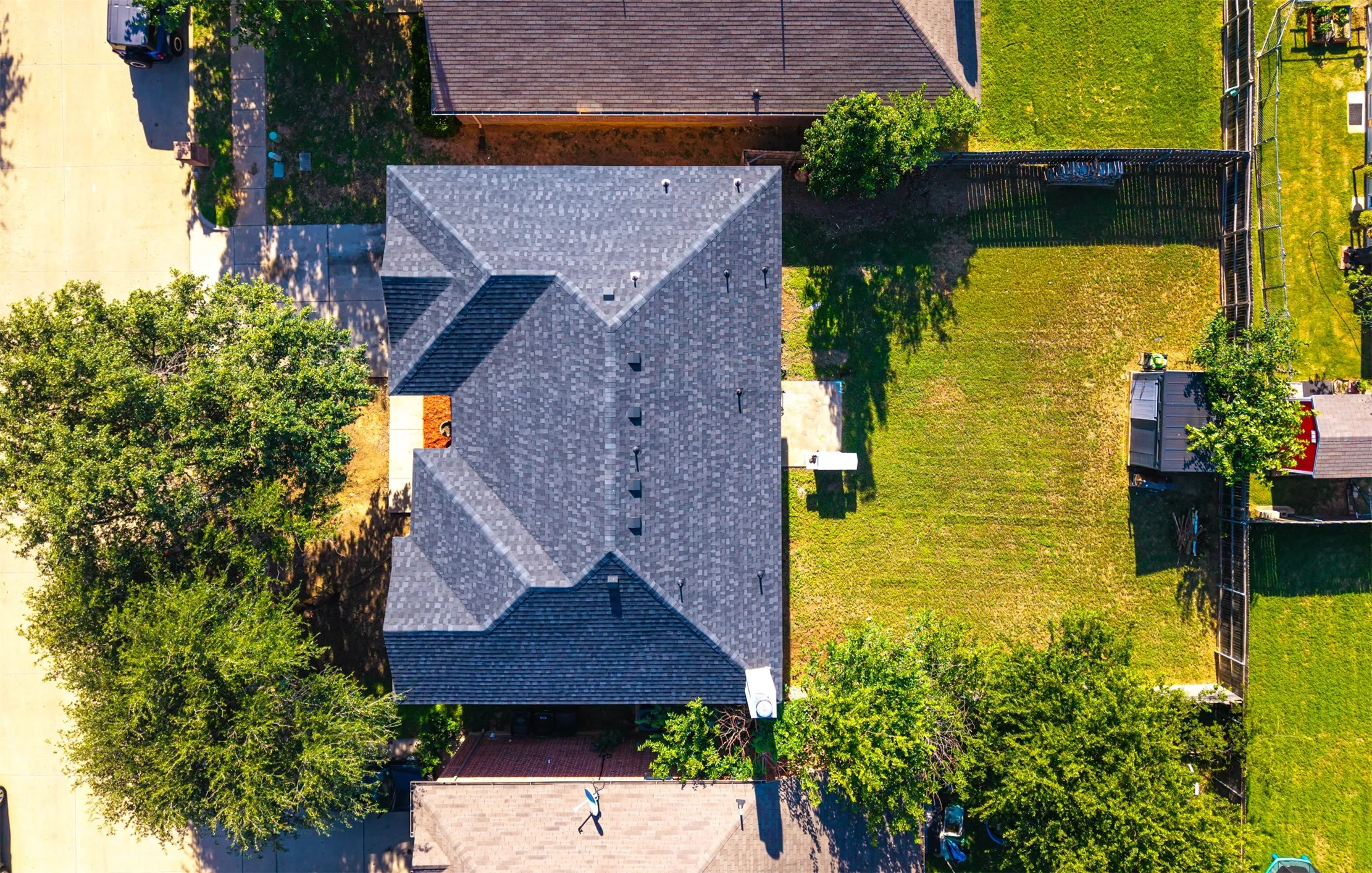 Expansive backyard featuring a manicured lawn, established perimeter fencing, and a dedicated storage shed