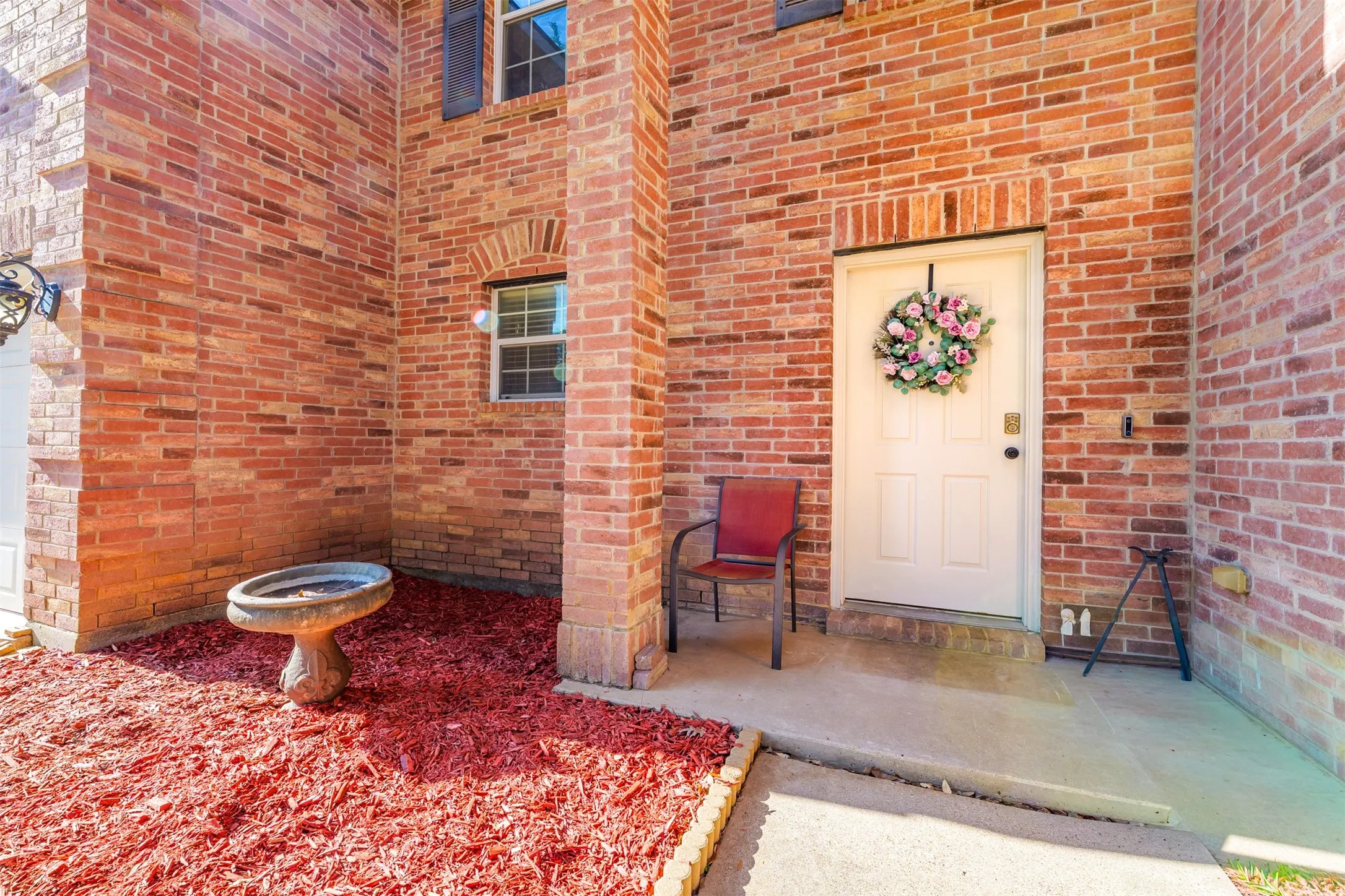 Brick facade featuring a white entry door, an arched window, and a concrete porch