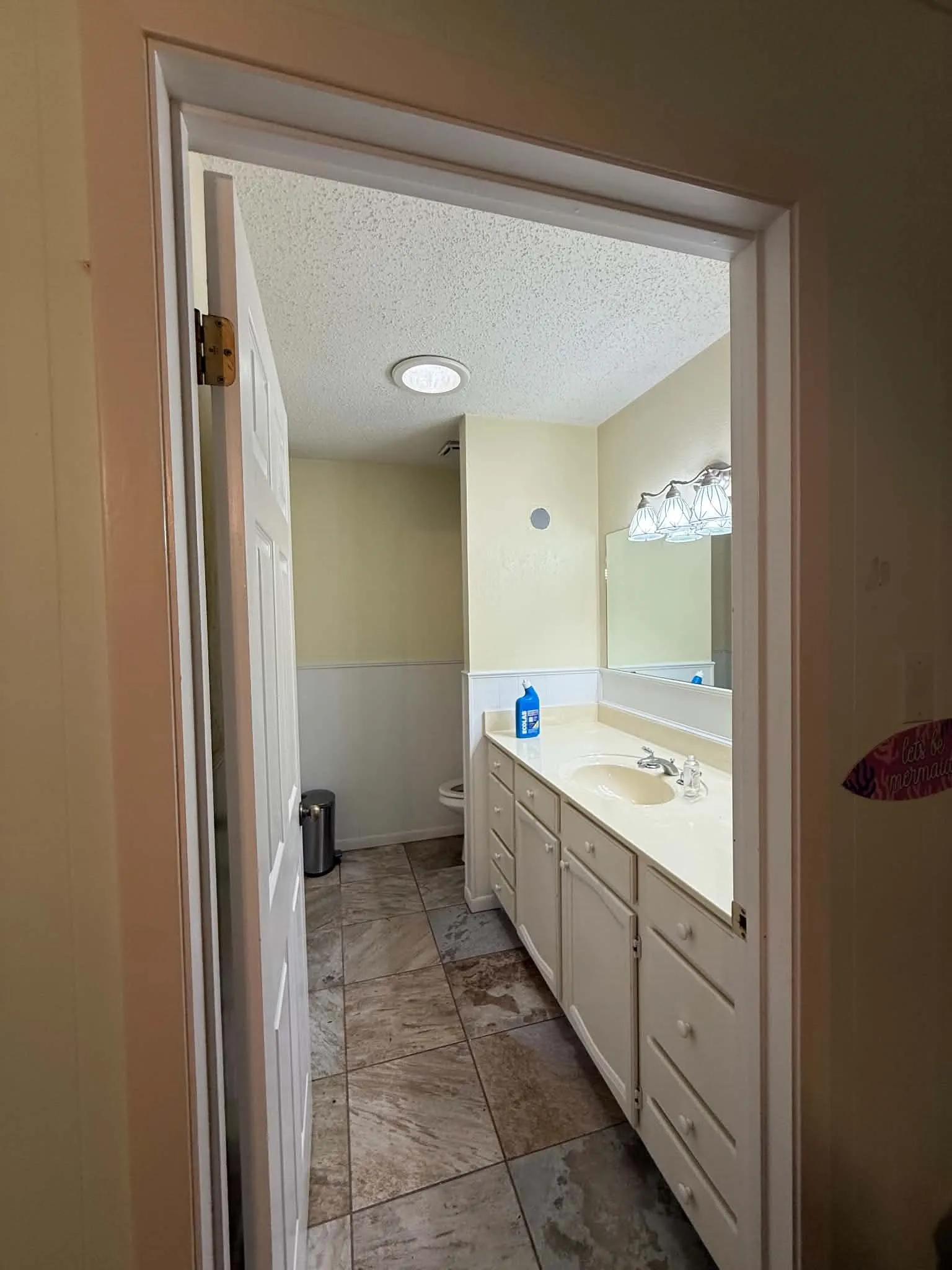 Bathroom with tiled flooring, an extended vanity with an integrated sink, and white cabinetry