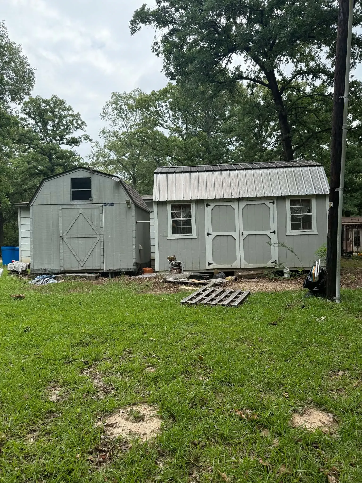 Two storage sheds with light gray siding and white trim