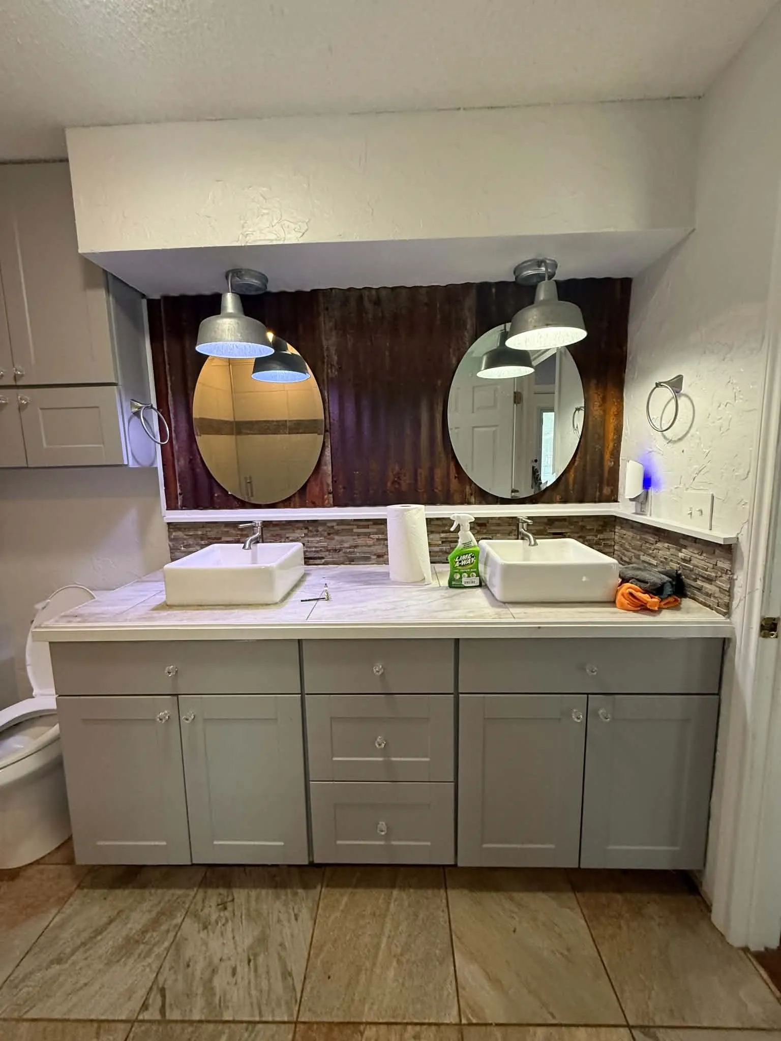 Double vanity featuring a light gray base cabinet with multiple storage drawers and doors, two white rectangular vessel sinks, and a light-toned countertop