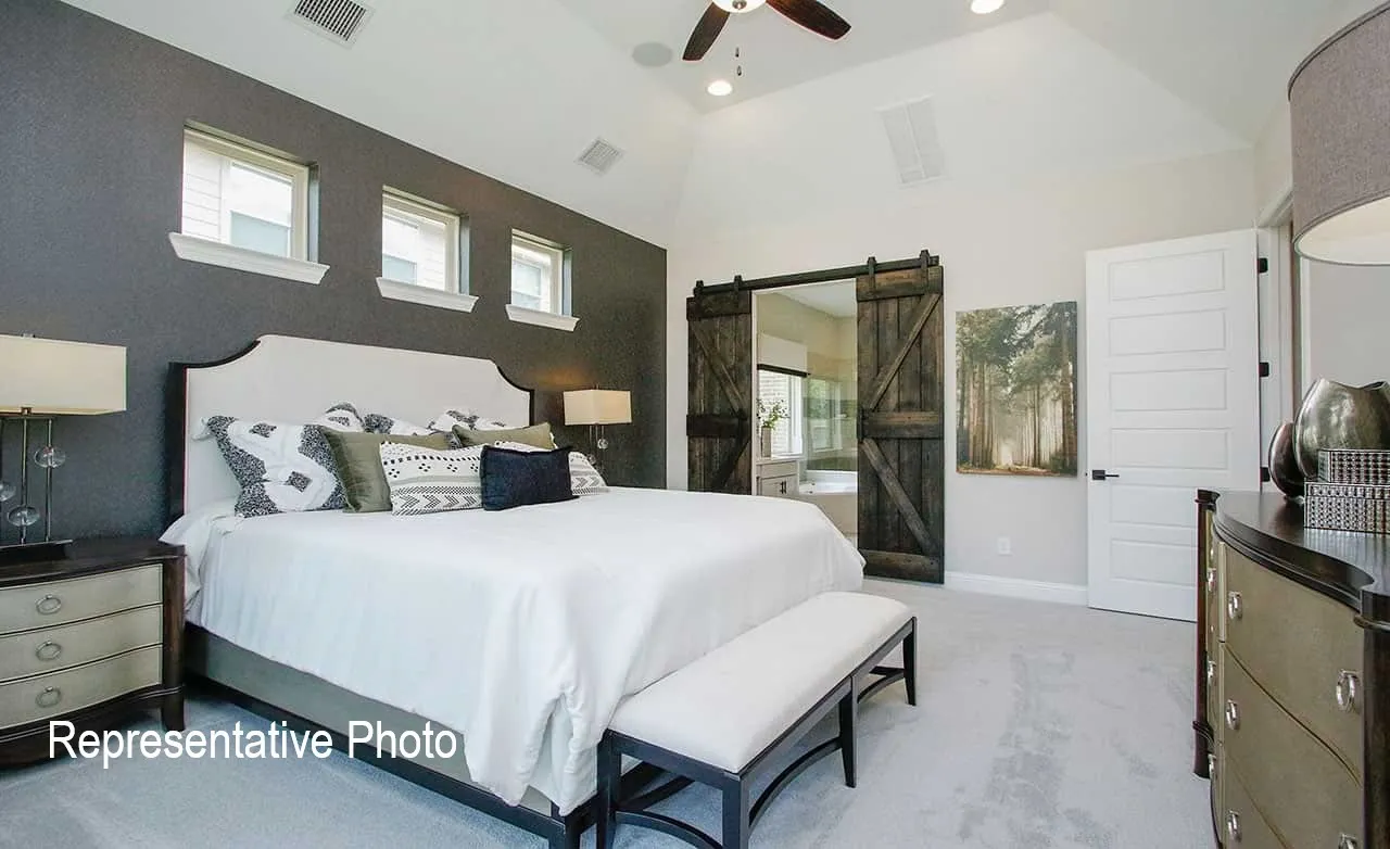 Spacious bedroom featuring a vaulted ceiling, bay window, light grey carpeting, and a dark accent wall