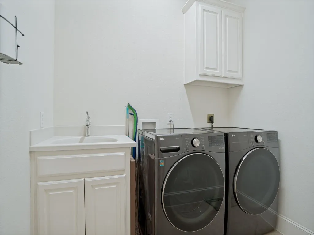     Spacious laundry room with built-in utility sink and ample storage for everyday convenience