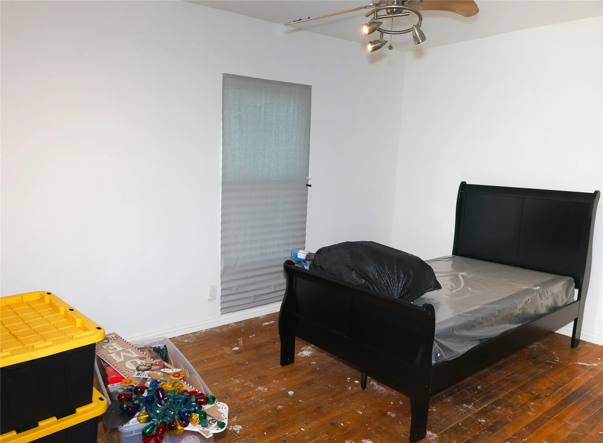 Room featuring wood-finish flooring, white walls, and a ceiling fan with integrated lighting