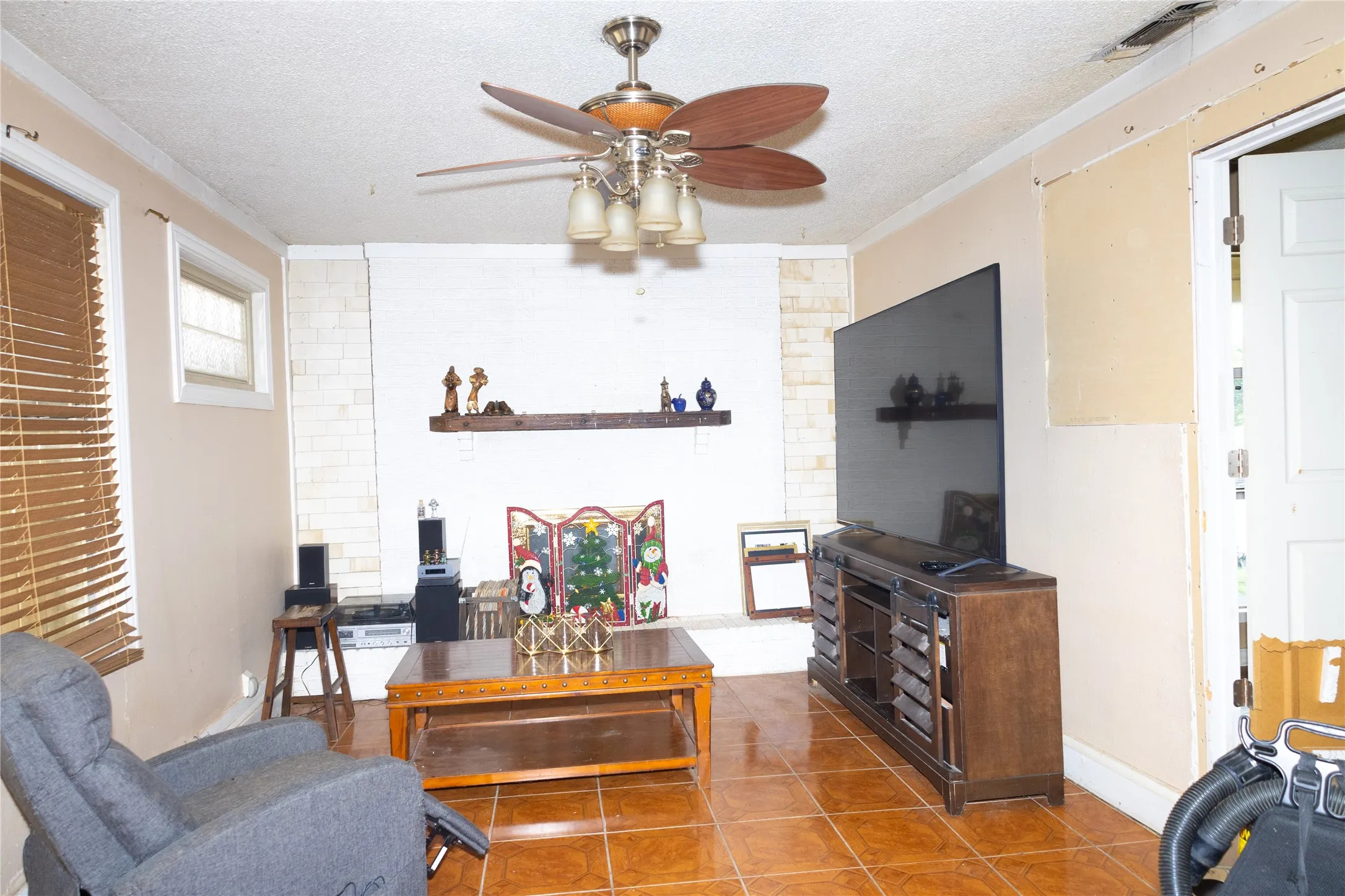 Living area featuring tile flooring, a ceiling fan with light fixture, and crown molding