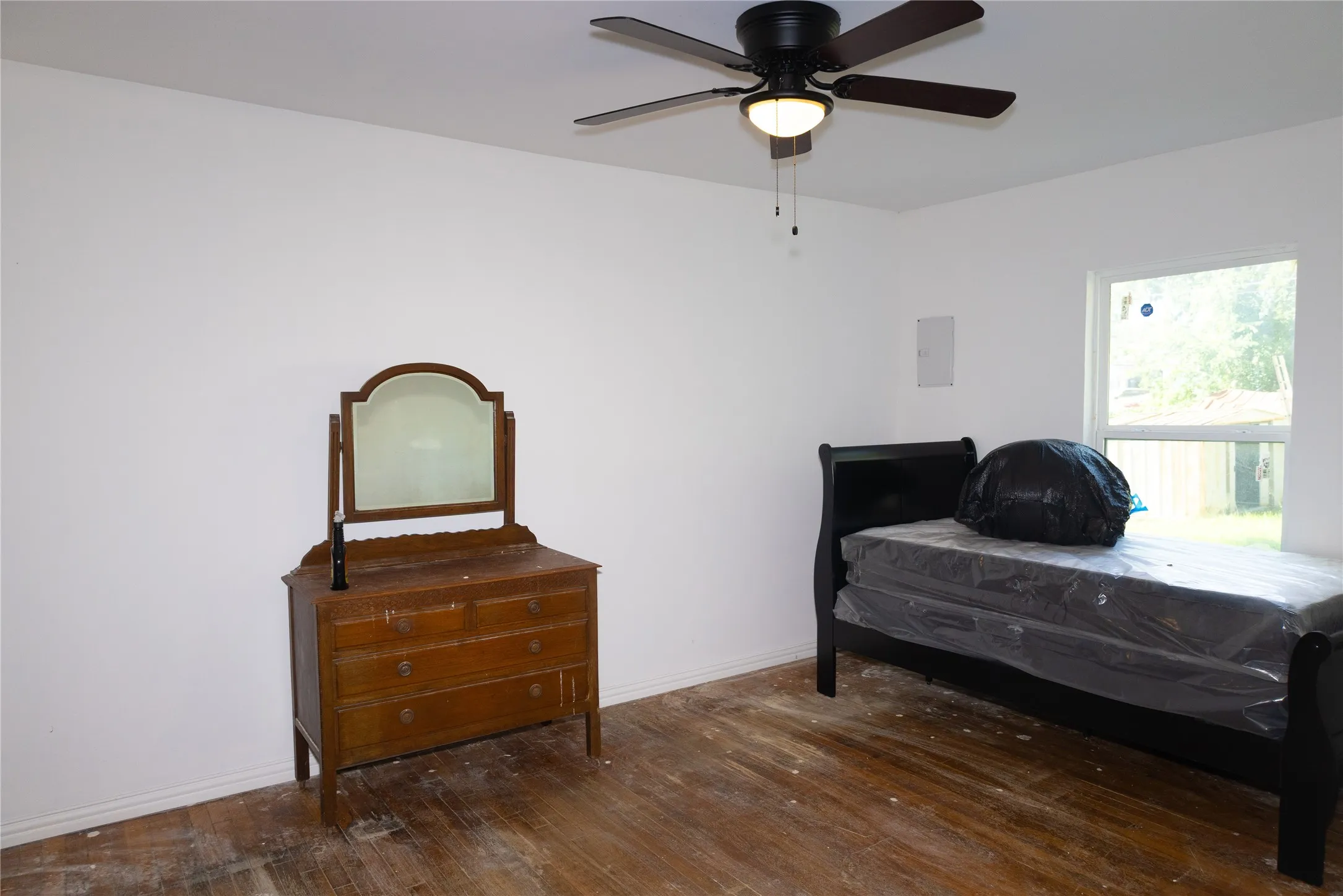 Room featuring wood-finish flooring, a ceiling fan with integrated lighting, and white painted walls