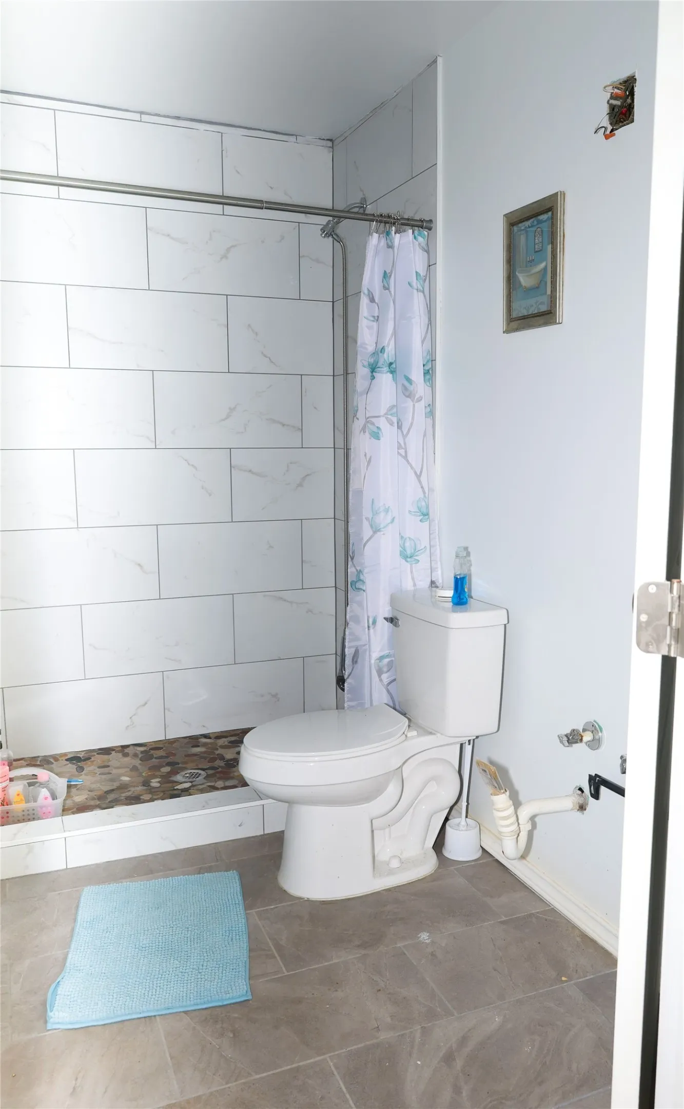 Walk-in shower with white tile surround and stone pebble base