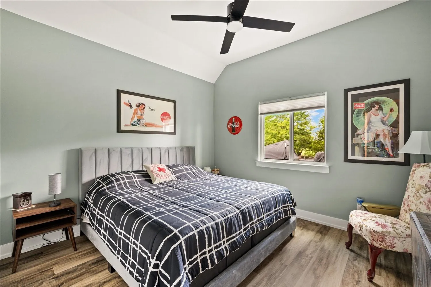 Room featuring vaulted ceilings with a ceiling fan, wood-finish flooring, and a large window