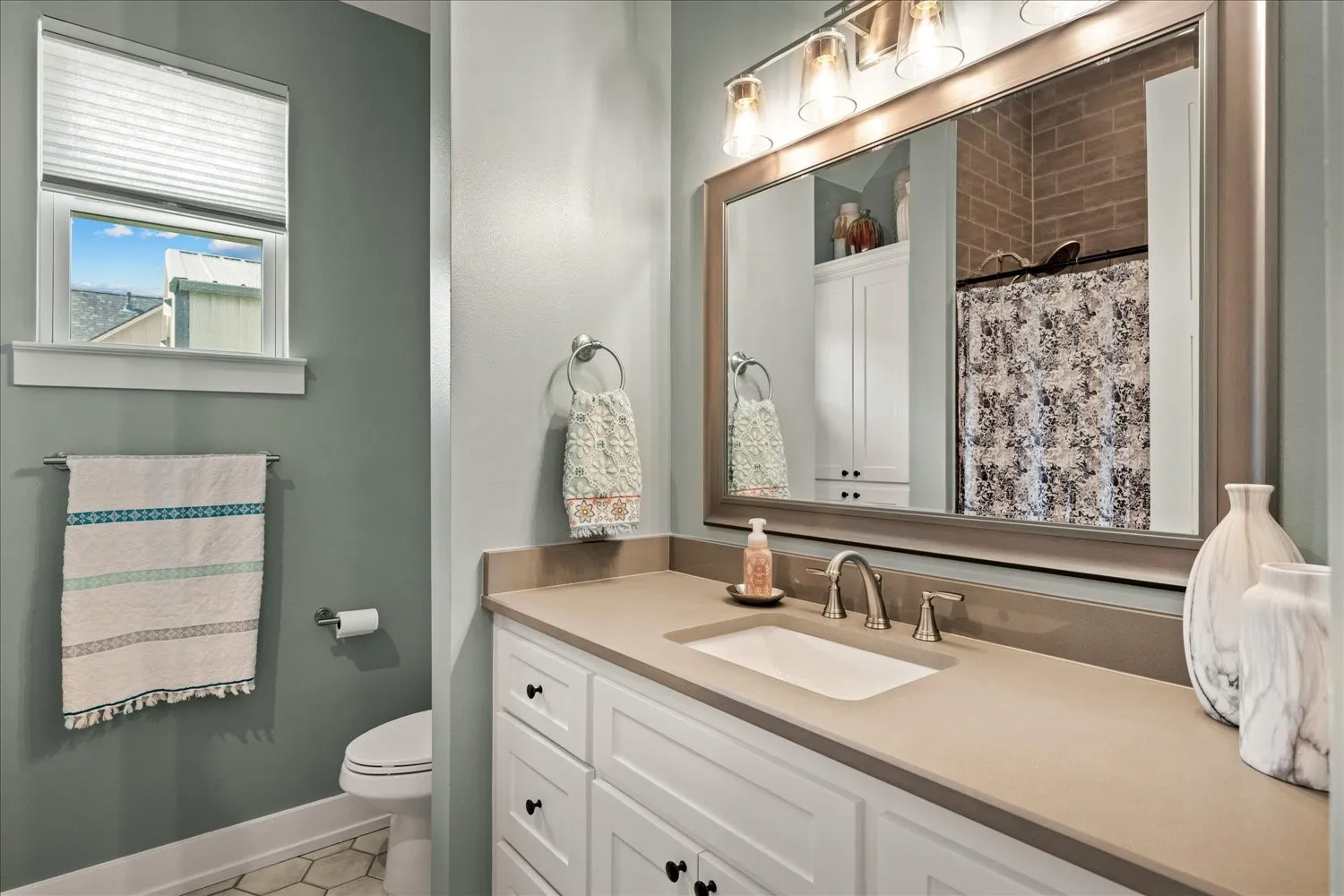 Bathroom vanity featuring a light-toned countertop, undermount sink, and brushed nickel faucet