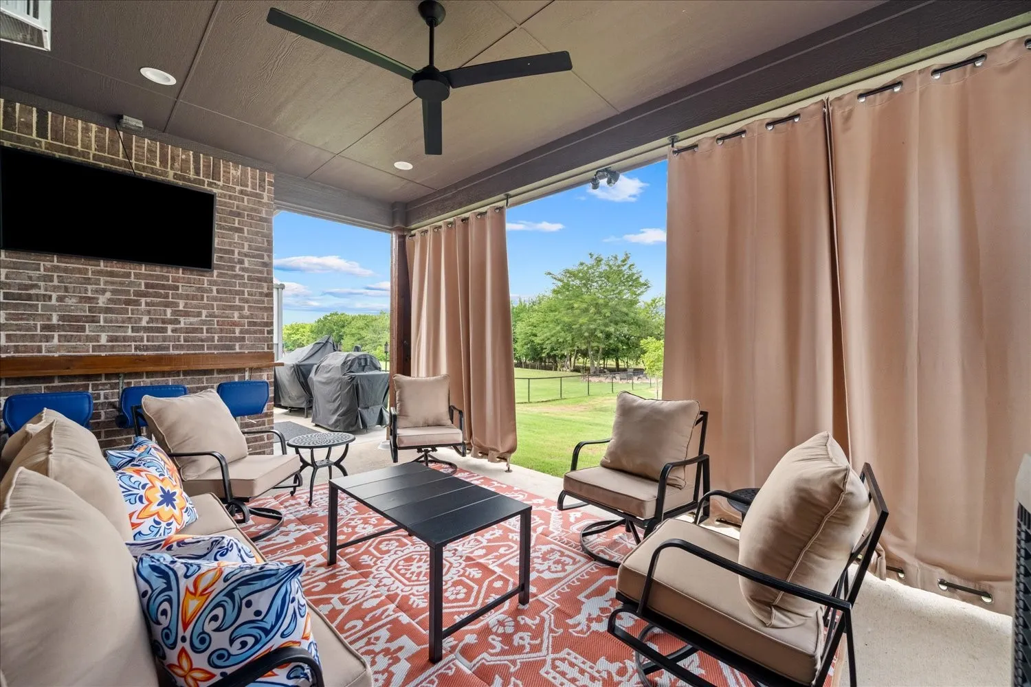 Covered outdoor patio featuring a brick accent wall, recessed lighting, and a ceiling fan