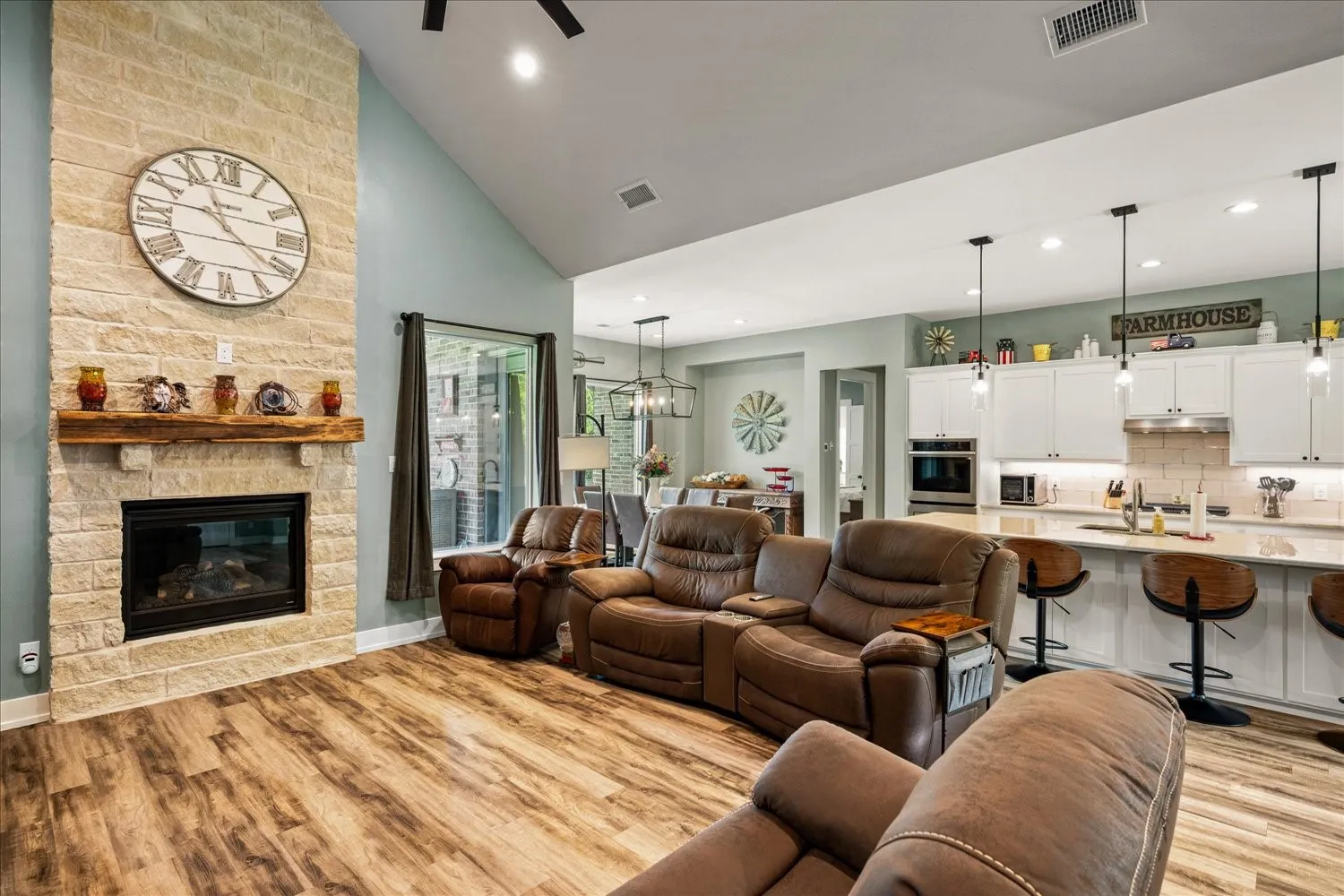 Vaulted ceiling great room featuring a stone fireplace with a substantial wood mantel