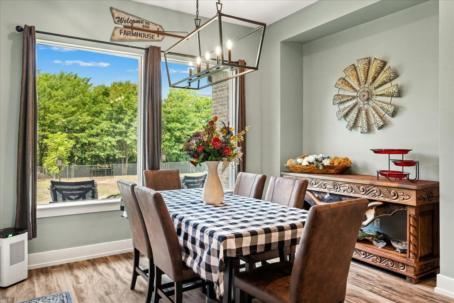 Dining area featuring wood-finish flooring, a large window, and a linear chandelier