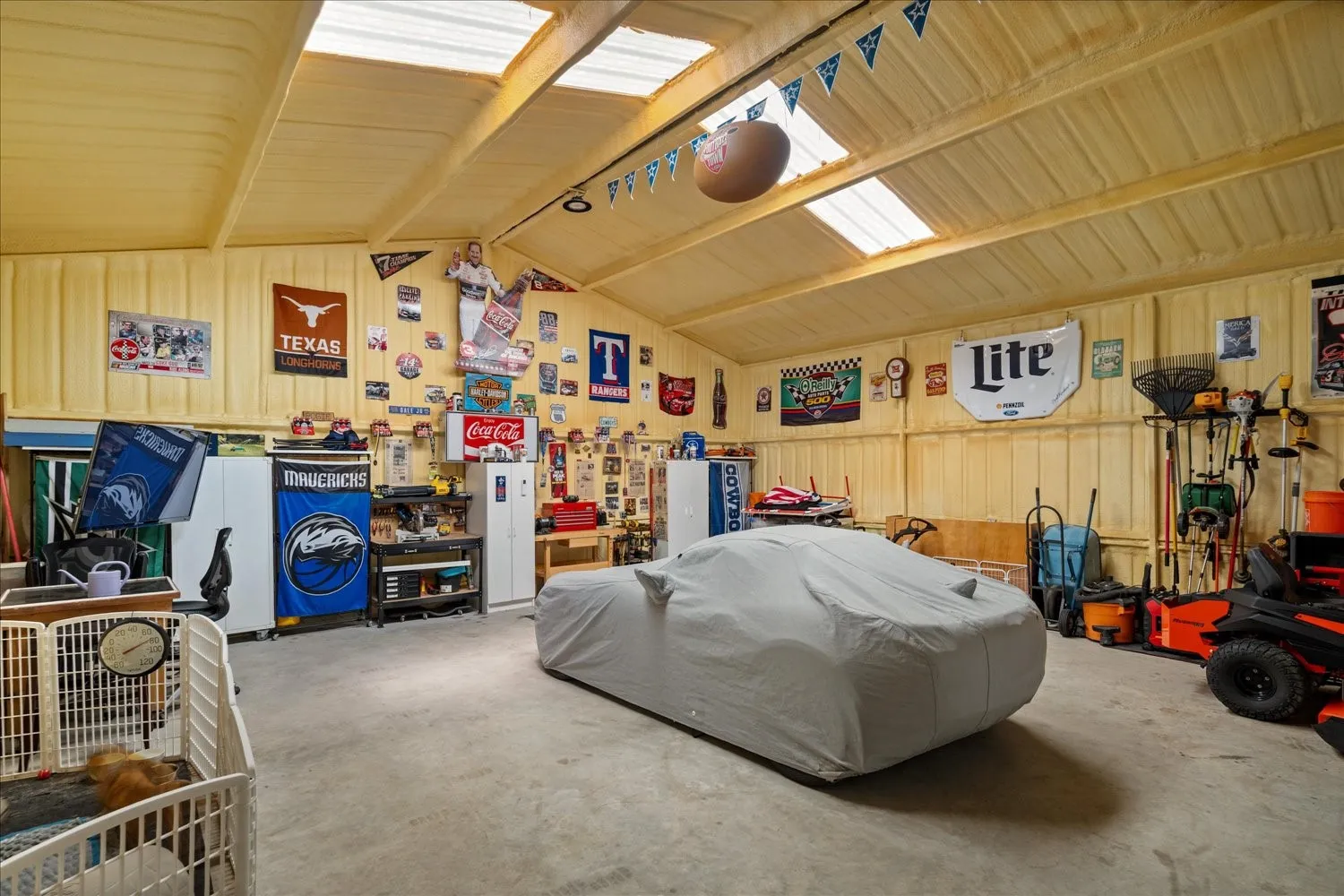 Spacious garage featuring a concrete floor, vaulted ceiling with skylights, and insulated walls