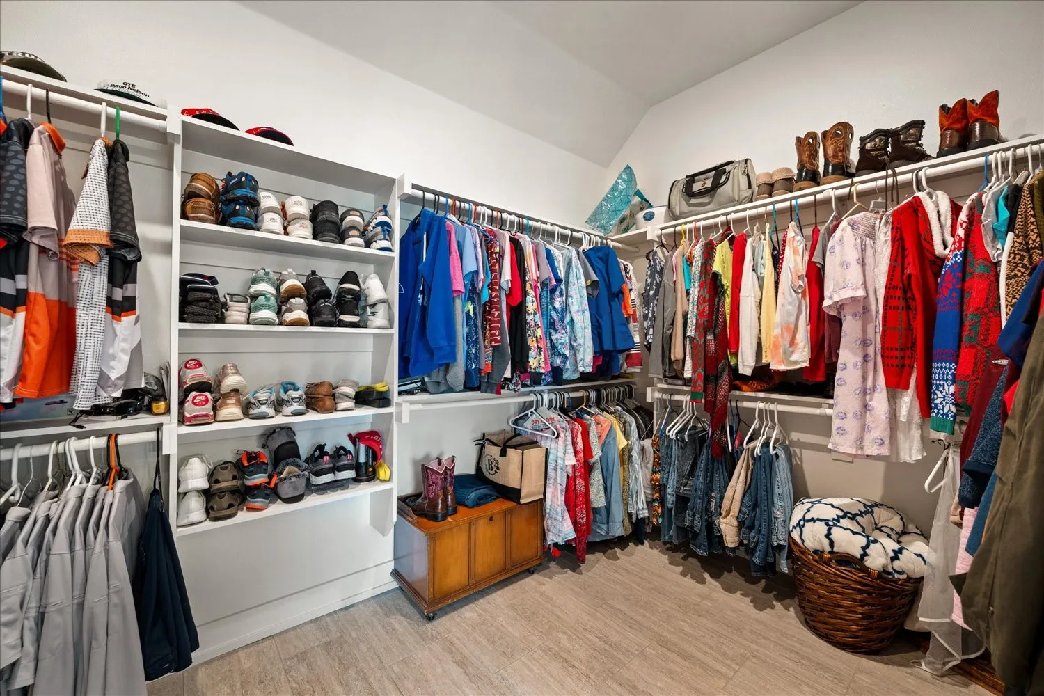 Custom closet system featuring extensive shelving, multiple hanging rods, corner storage, and wood-finish flooring