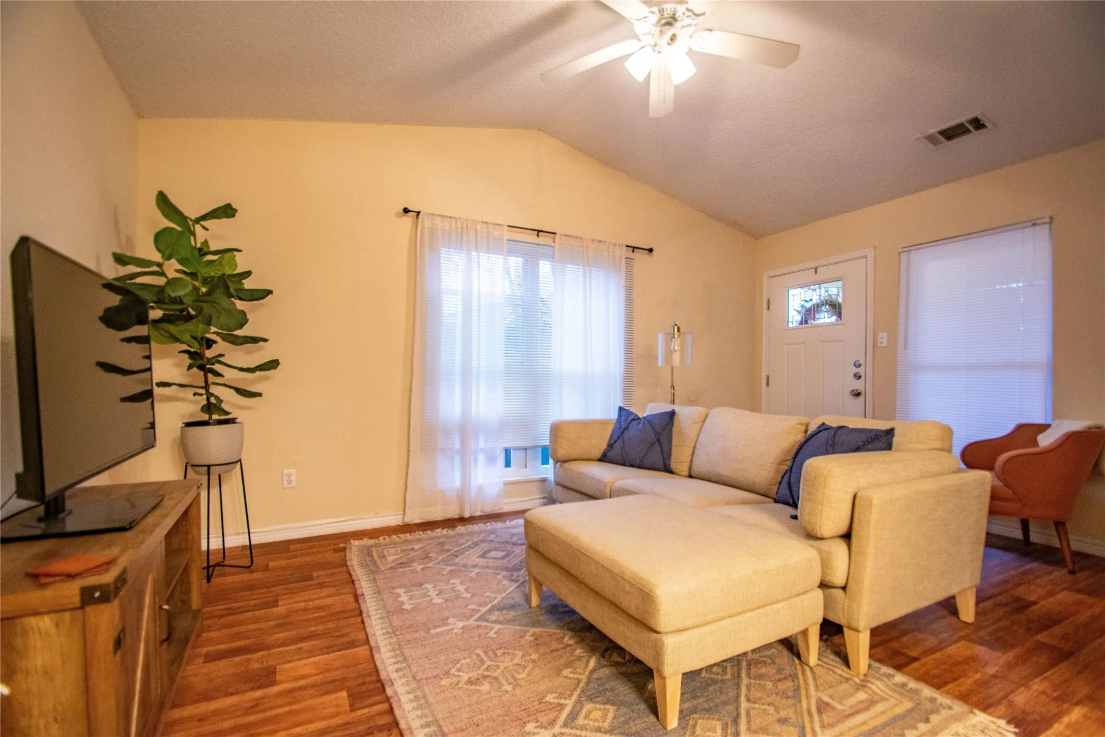 Living room featuring lofted ceiling, ceiling fan, and dark wood-type flooring