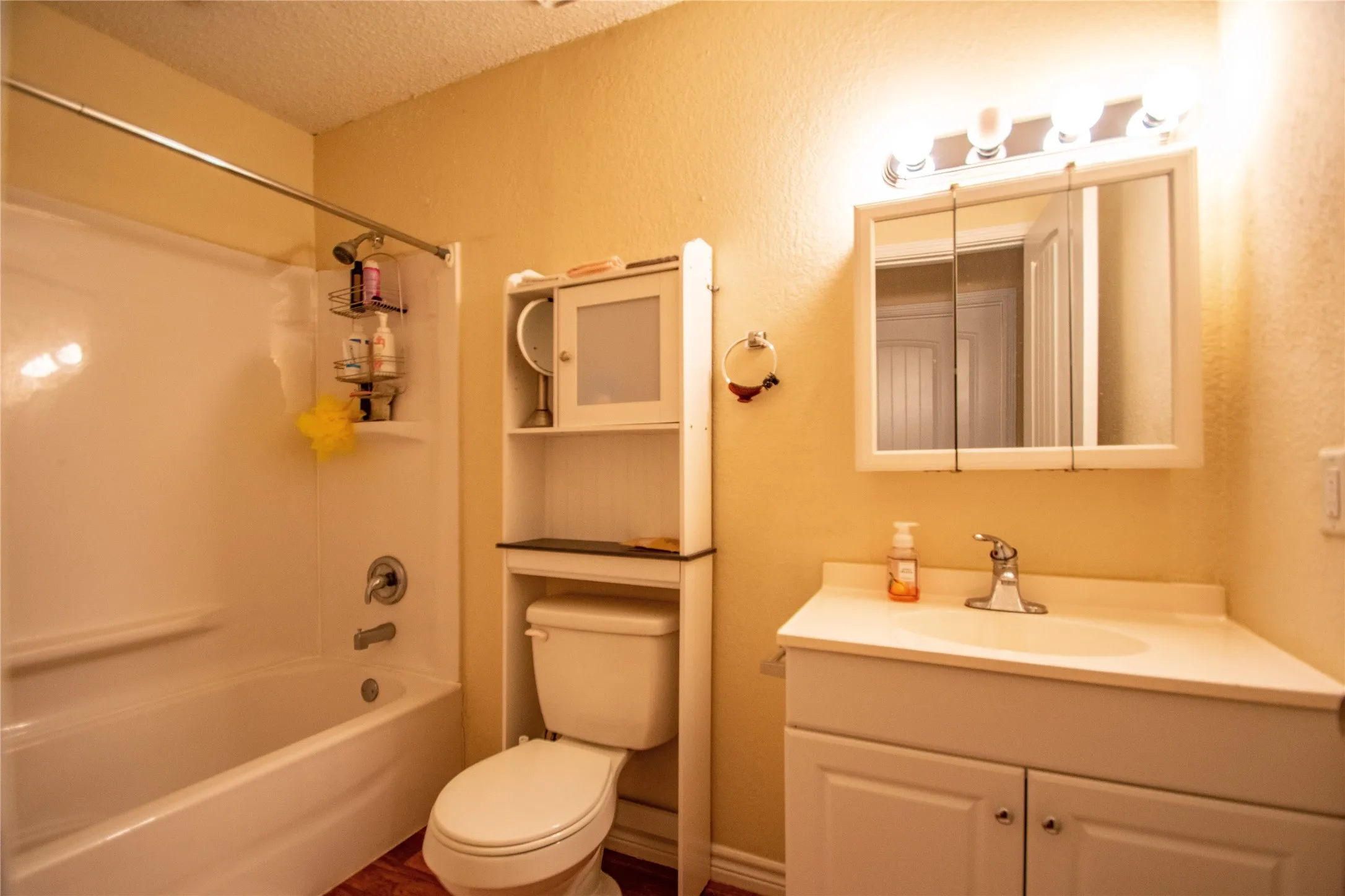 Full bathroom featuring washtub / shower combination, vanity, toilet, and a textured ceiling