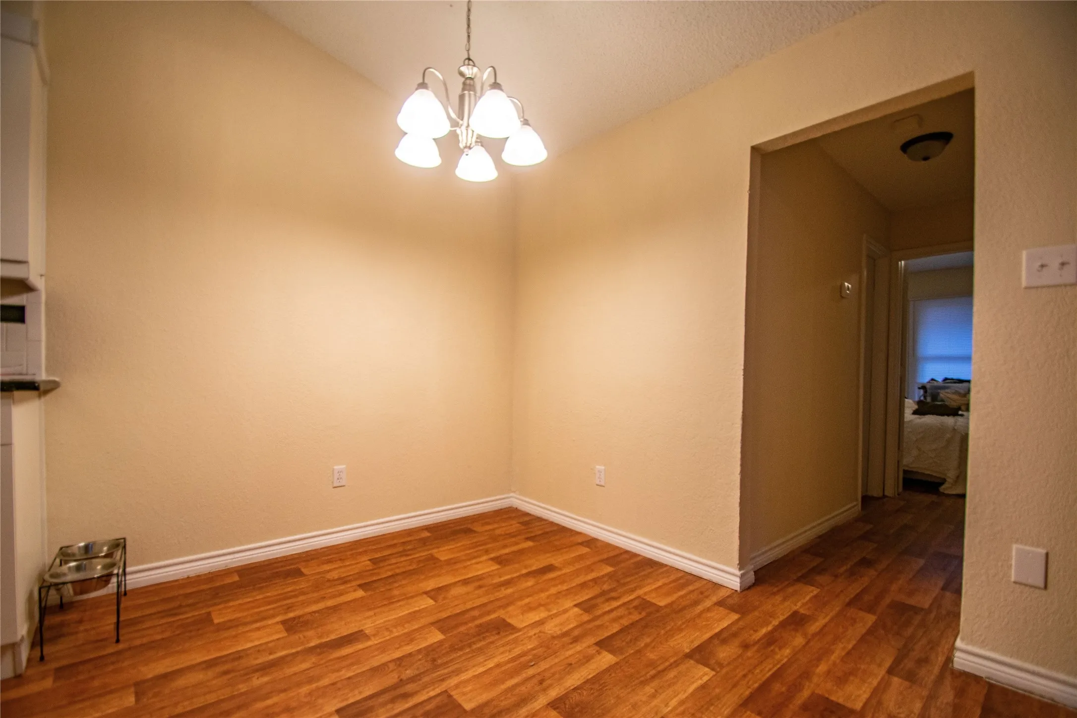 Spare room featuring dark hardwood / wood-style flooring, a chandelier, and vaulted ceiling