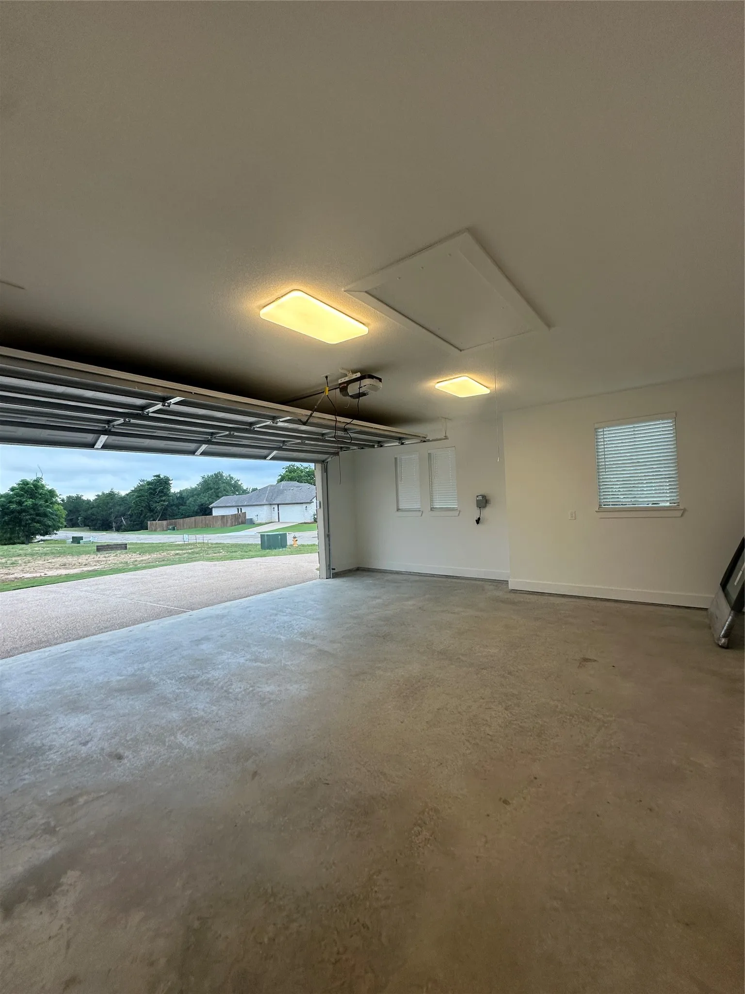 Spacious garage featuring a concrete floor, overhead lighting, and an automatic garage door opener