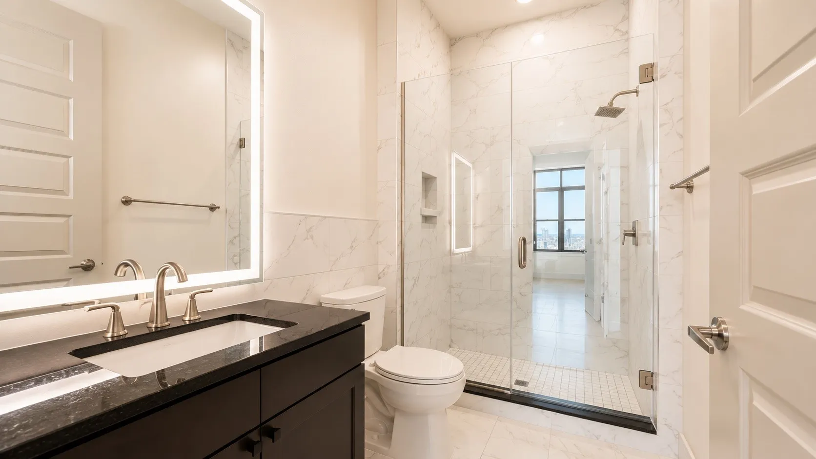 Contemporary bathroom featuring a dark wood vanity with a black countertop and an integrated sink, illuminated by a backlit mirror
