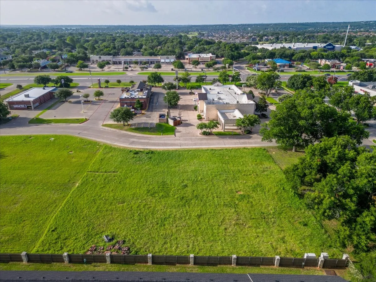 Expansive undeveloped lot featuring a perimeter fence and surrounding mature trees