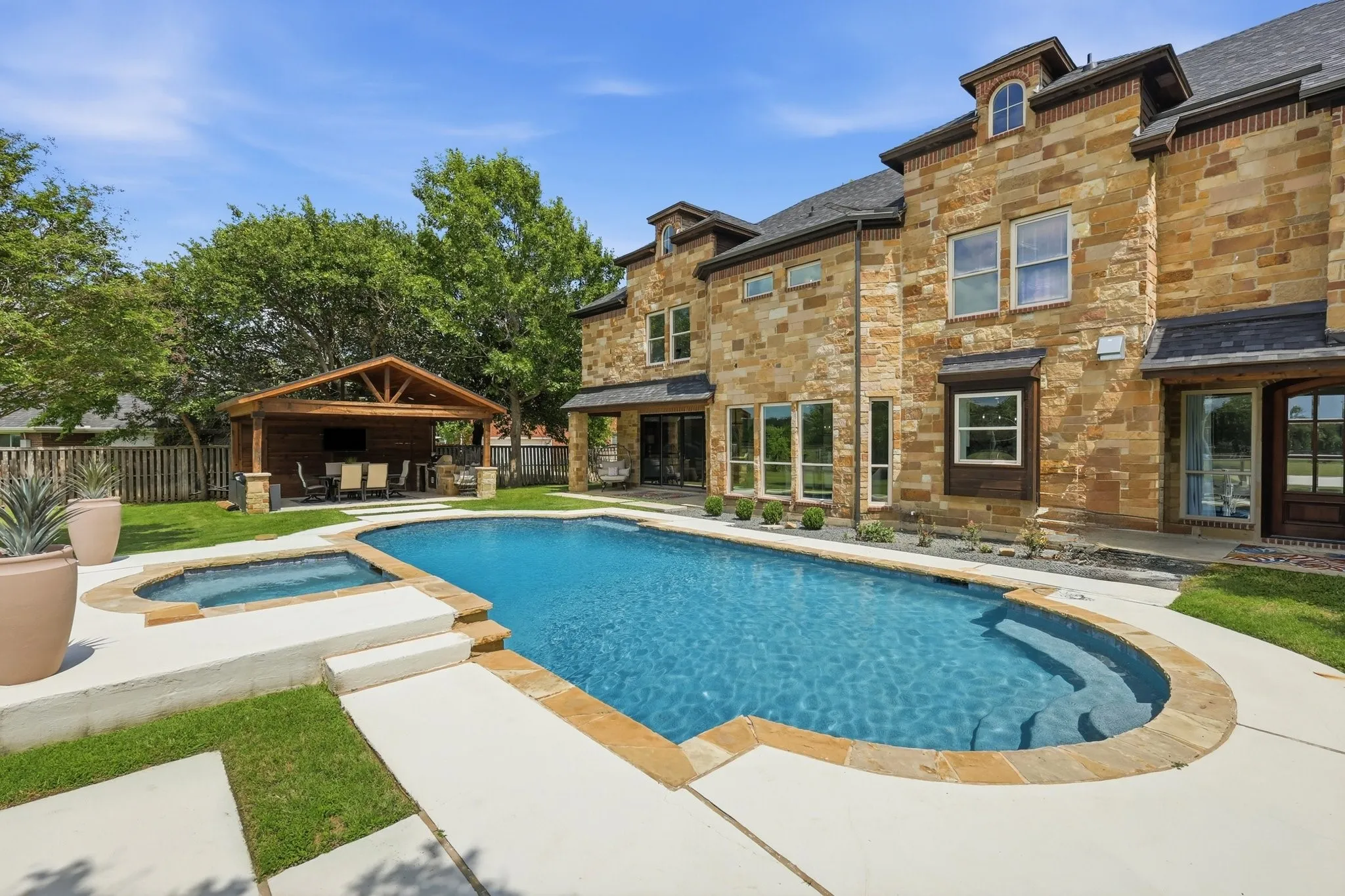 210 Canyon Oaks, Argyle, TX 76226 - Pool and yard - Expansive backyard featuring a rectangular pool with integrated spa, a dedicated outdoor kitchen, and a stone-clad exterior