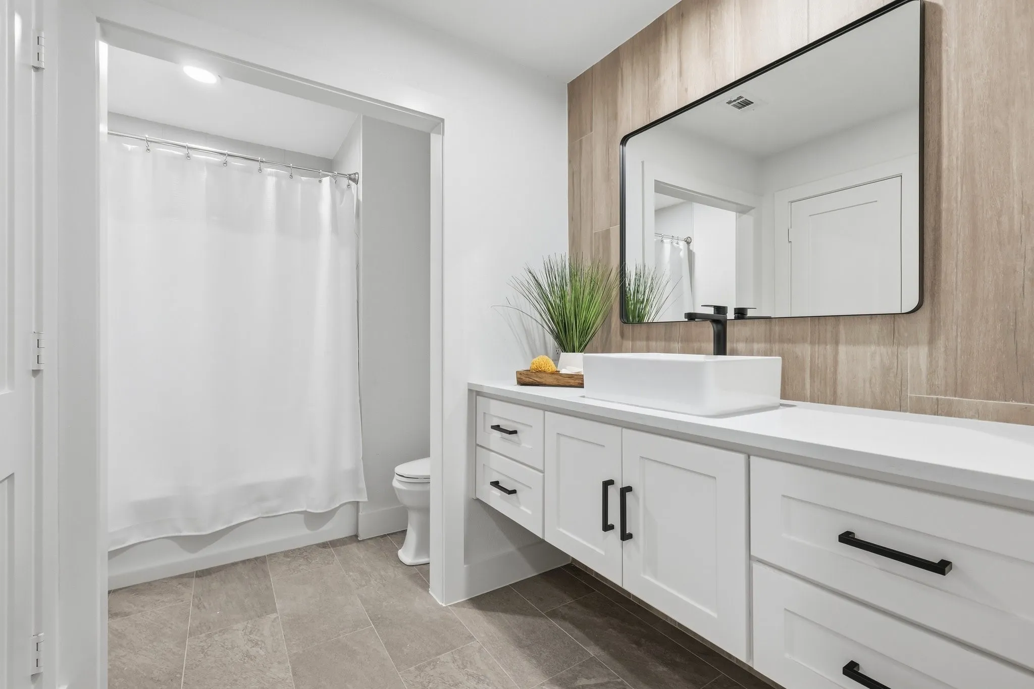 210 Canyon Oaks, Argyle, TX 76226 - Bathroom - Modern bathroom featuring a floating white vanity with a vessel sink, a matte black wall-mounted faucet, and a rectangular mirror with a black frame