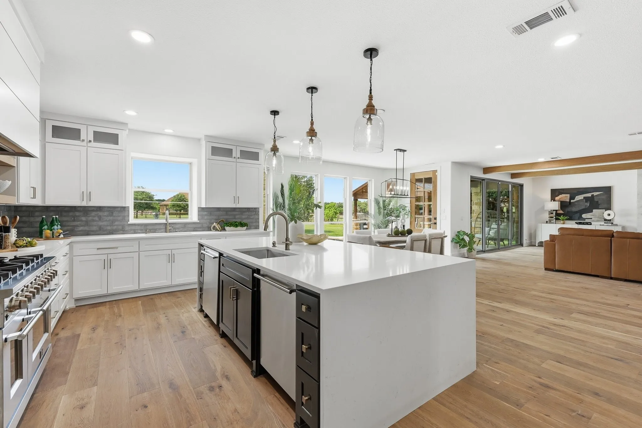 210 Canyon Oaks, Argyle, TX 76226 - Kitchen - Open-concept kitchen featuring an expansive island with an integrated sink, white shaker cabinetry, stainless steel appliances, and wood-finish flooring