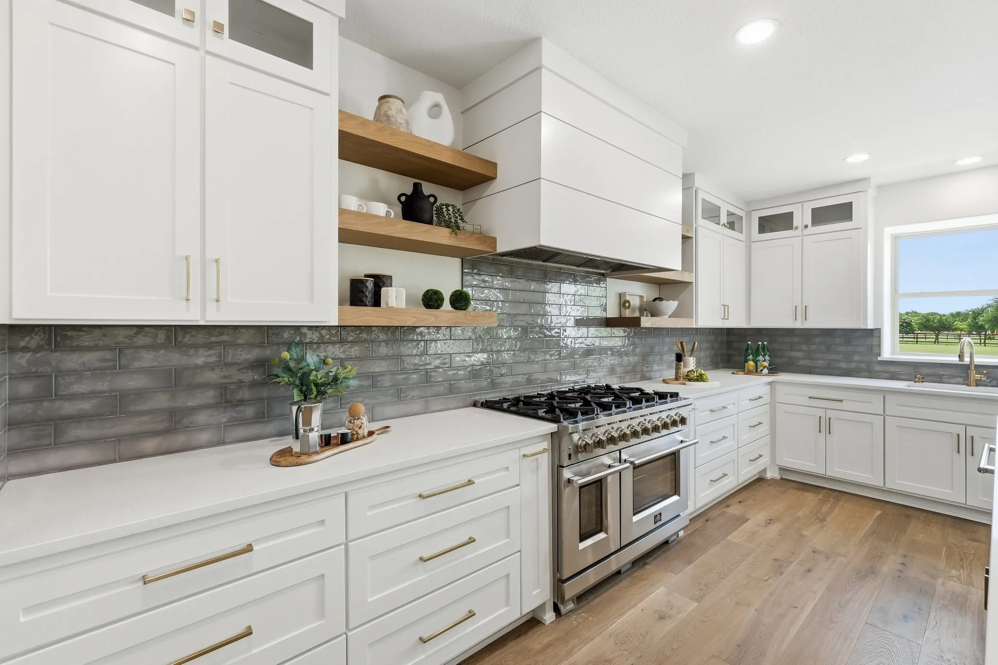 210 Canyon Oaks, Argyle, TX 76226 - Kitchen - Gourmet kitchen featuring a stainless steel range, white shaker-style cabinetry, light countertops, a dark subway tile backsplash, and light wood-finish flooring