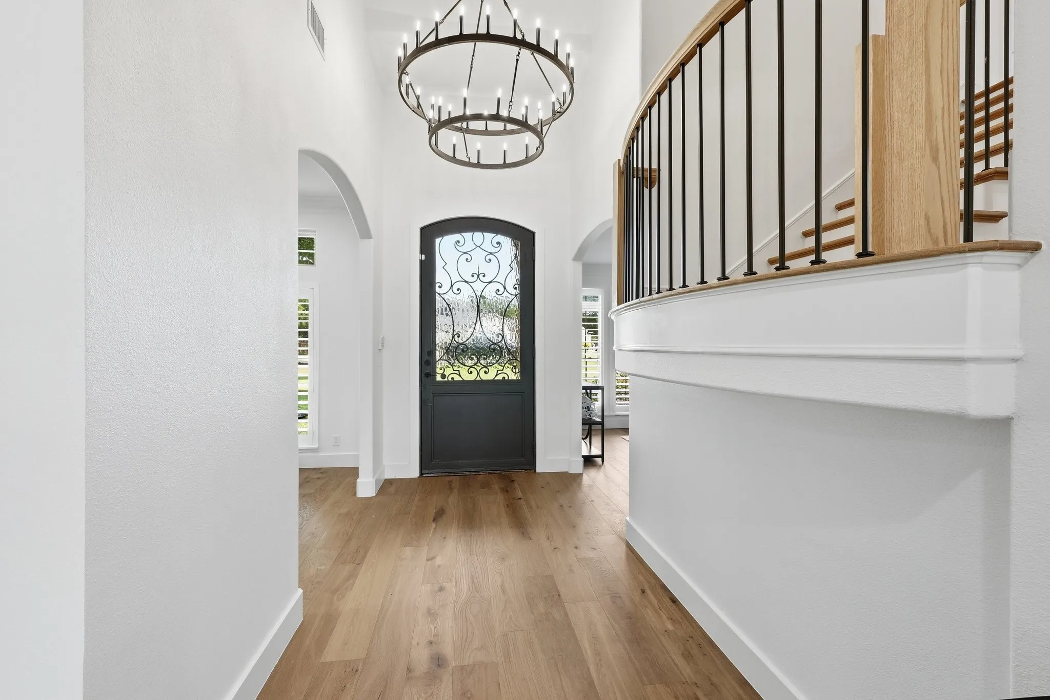 210 Canyon Oaks, Argyle, TX 76226 - Entrance - Grand entry foyer featuring a custom wrought iron and glass front door, two-story ceiling, wood-finish flooring, and arched doorways
