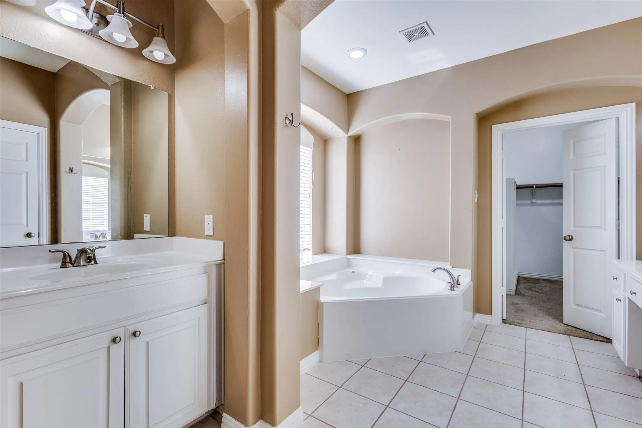 Bathroom with vanity, walk-in closet access, and light tile-patterned flooring, adding storage, convenience, and everyday functionality in this Collin County home for sale, ideal for buyers seeking a well-kept McKinney TX property with practical features and a highly livable layout