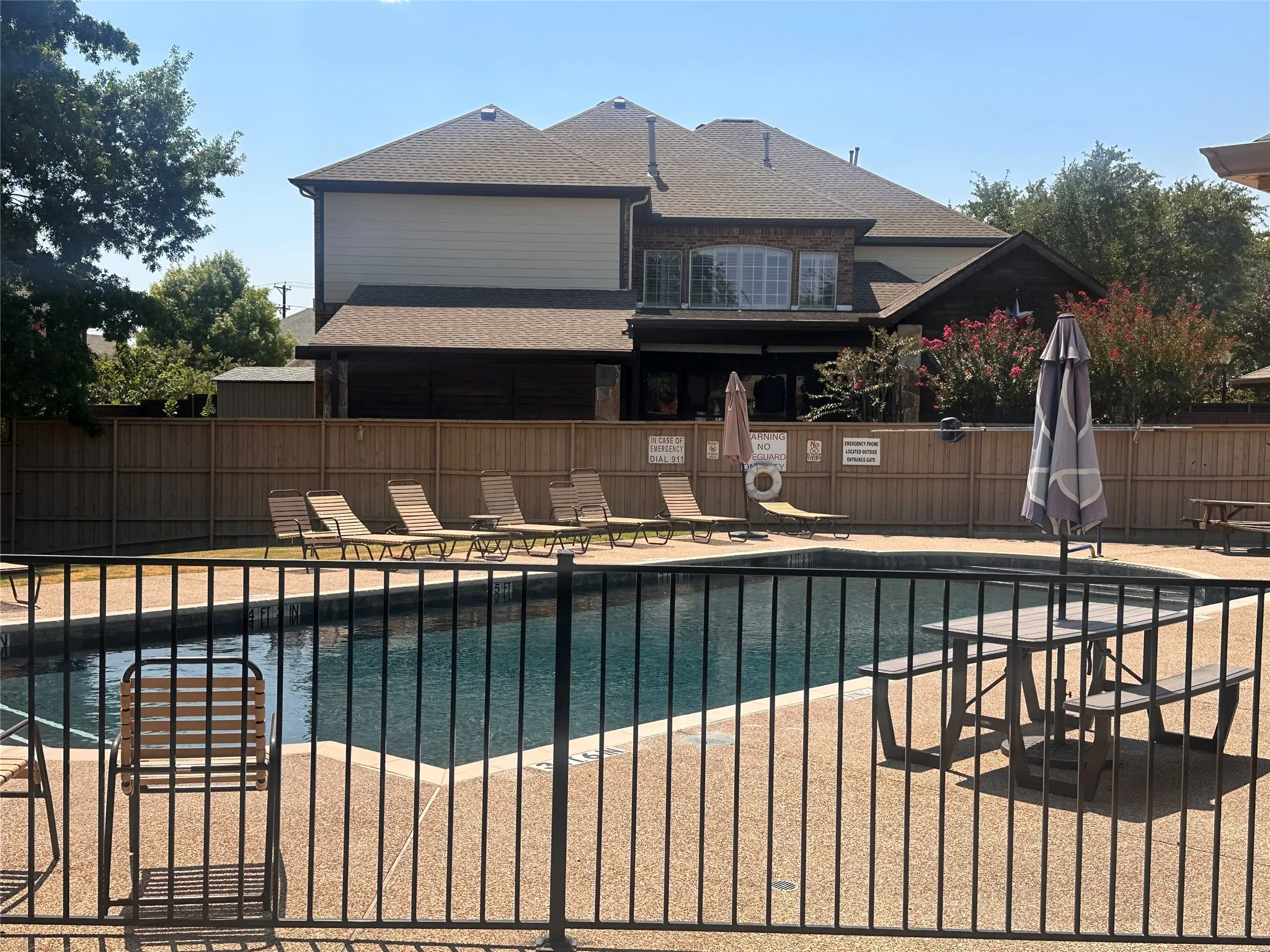 Fenced outdoor swimming pool with surrounding hardscaping and a perimeter safety fence