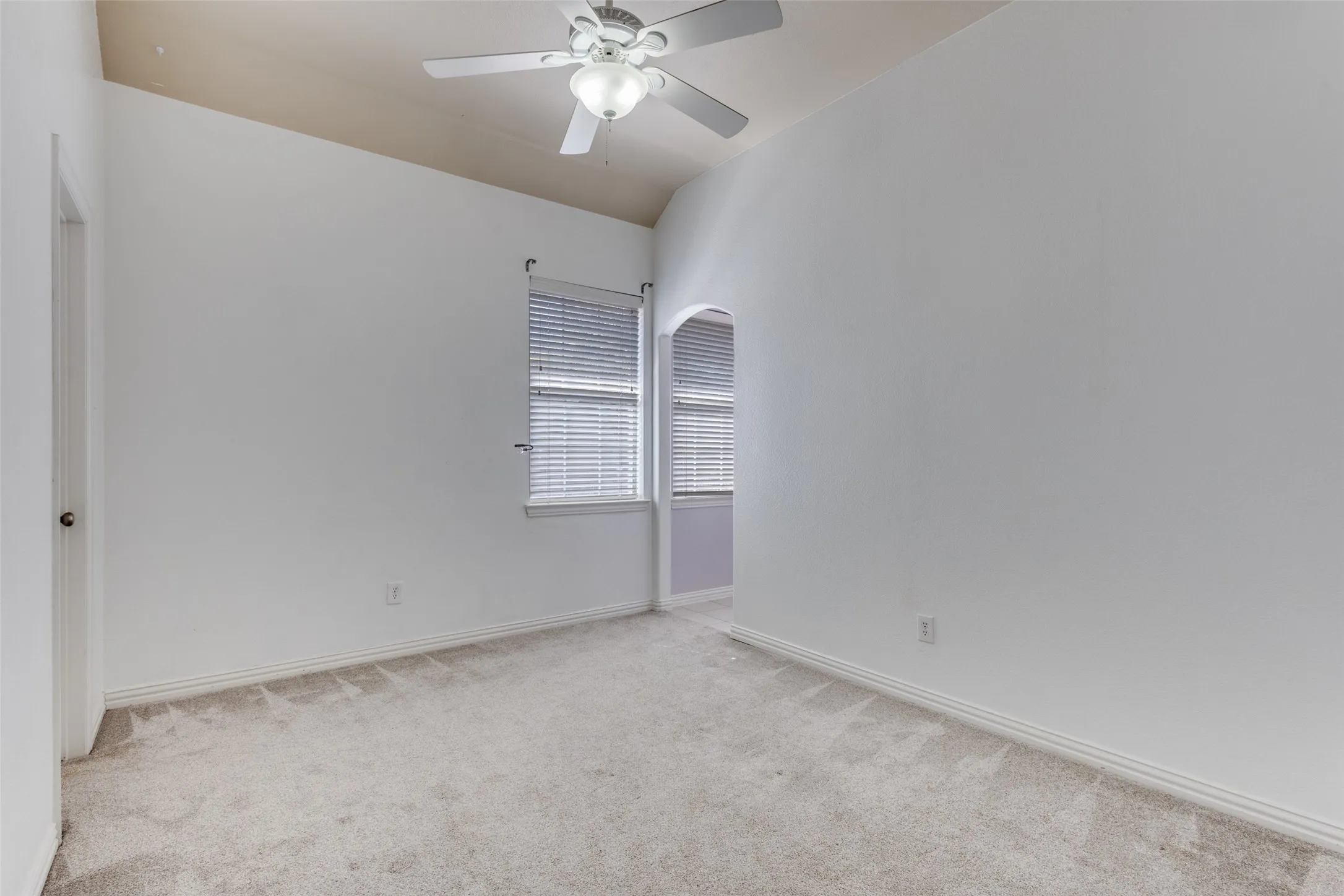 Flexible spare room with light-colored carpet, ceiling fan, and arched walkways, perfect for use as a guest bedroom, nursery, home office, playroom, hobby room, workout room, or bonus space in this McKinney TX home for buyers who value versatility, location, and a family-friendly layout.