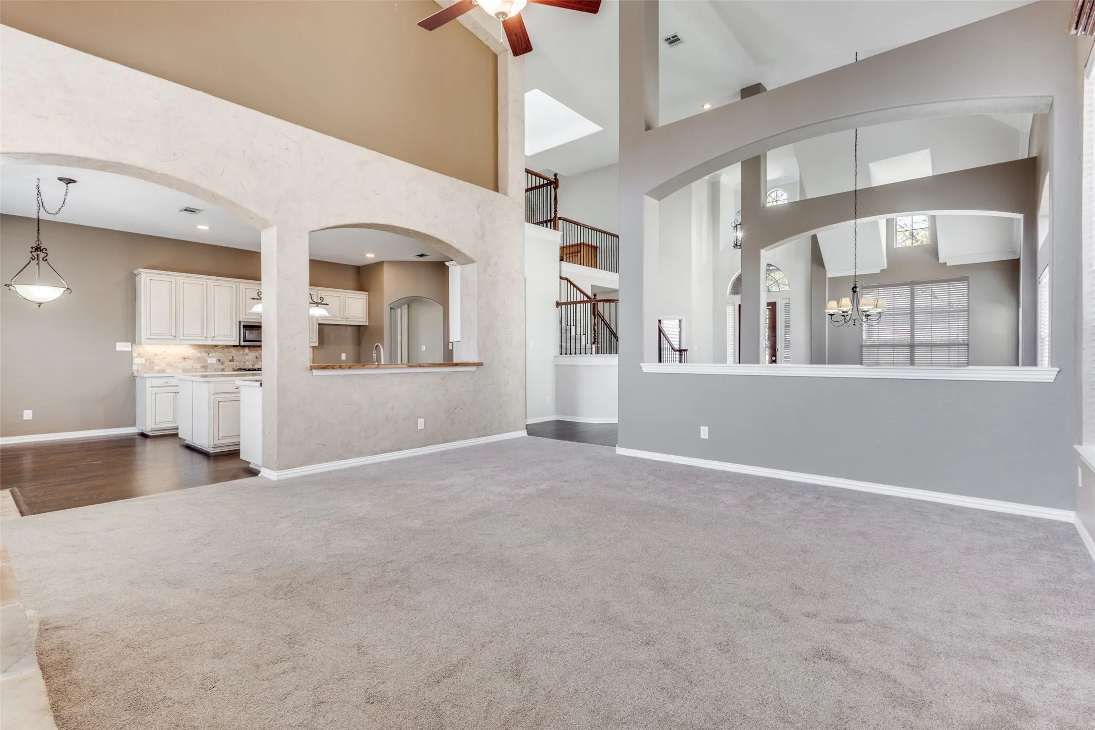 Secondary living space with ceiling fan, arched walkways, light carpet, suspended lighting, and high ceiling, offering additional flexible living space that works beautifully as a family room, sitting area, media-adjacent lounge, or second living zone in this spacious McKinney TX home in Collin County.