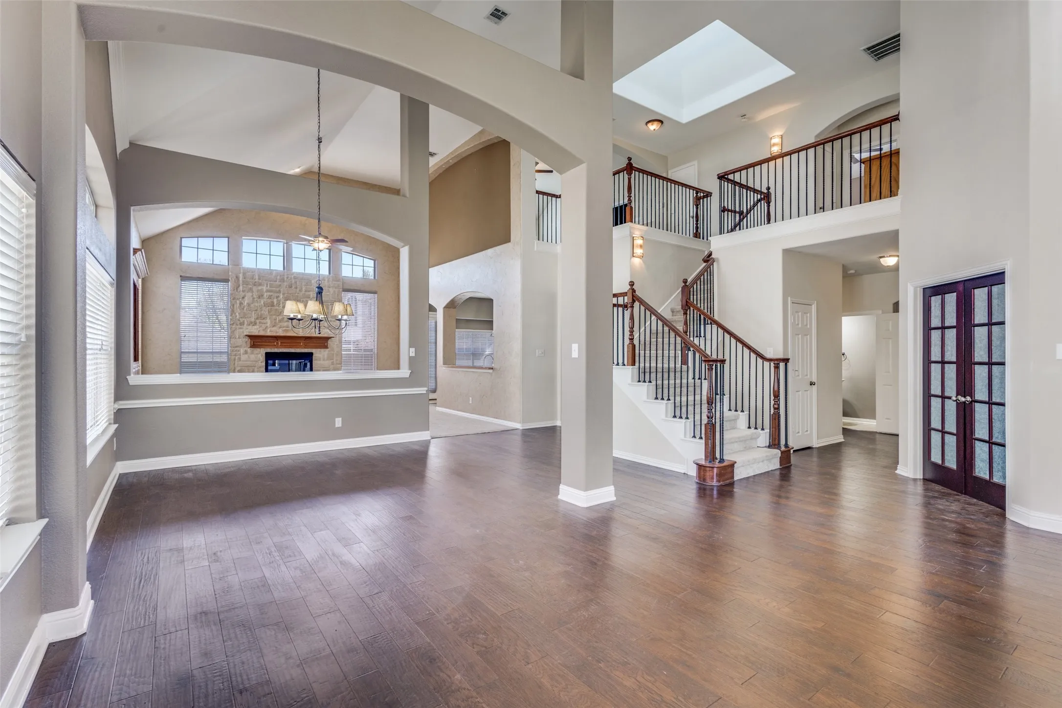 Elegant two-story entryway with French doors, dark wood flooring, a decorative glass fireplace feature, high ceiling, lofted architectural opening, and upscale traditional styling, perfect for buyers seeking a spacious McKinney home in Virginia Woods with luxury character, natural light, and proximity to Historic Downtown McKinney, Highway 75, and McKinney ISD schools.