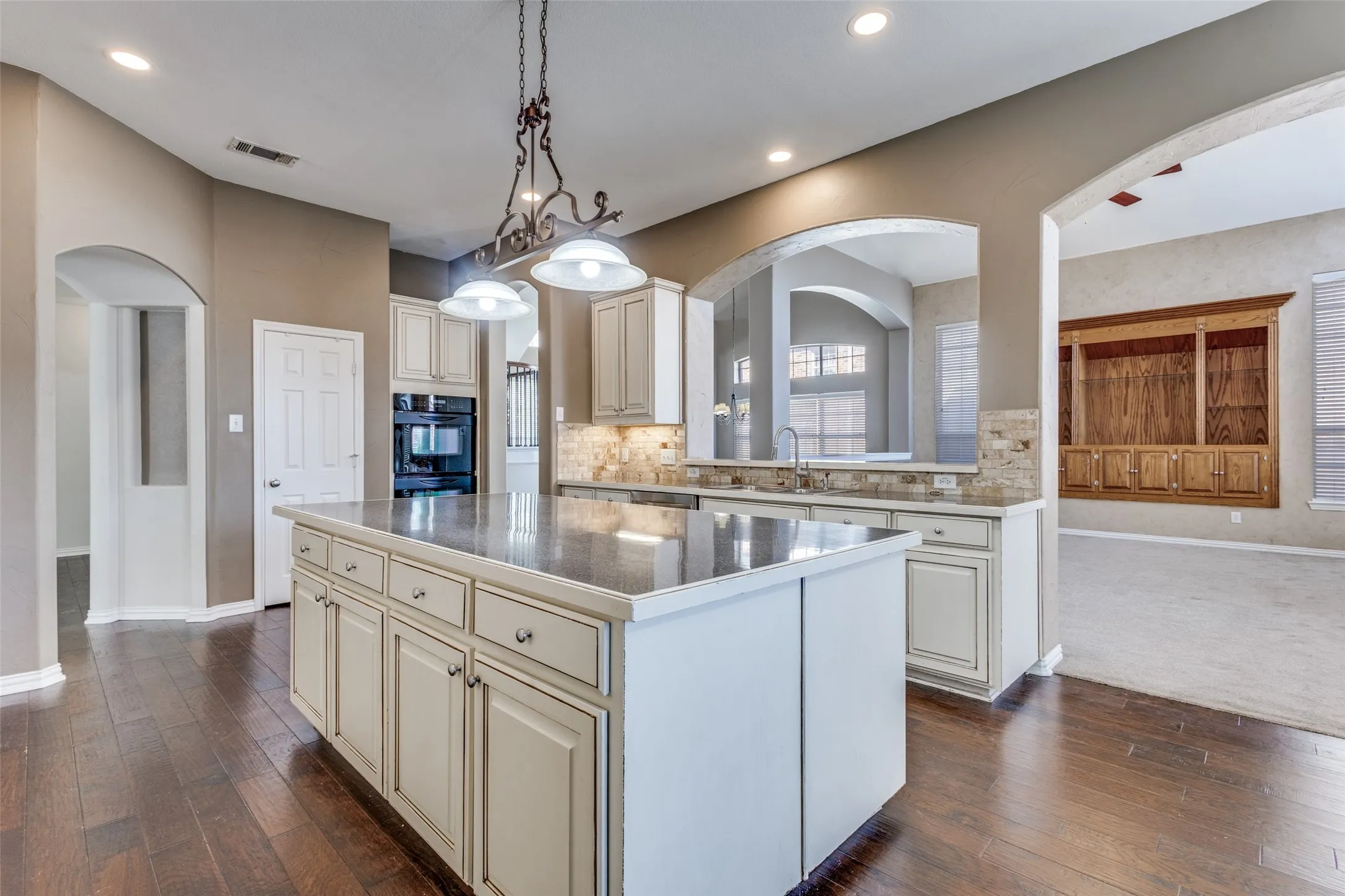 Gourmet chef’s kitchen with arched walkways, large kitchen island, cream cabinetry, decorative lighting, dark wood flooring, and a functional open layout, ideal for buyers looking for a McKinney Texas home with upgraded kitchen features, entertaining space, and strong keyword appeal for Virginia Woods, Collin County, and the greater North Dallas real estate market.