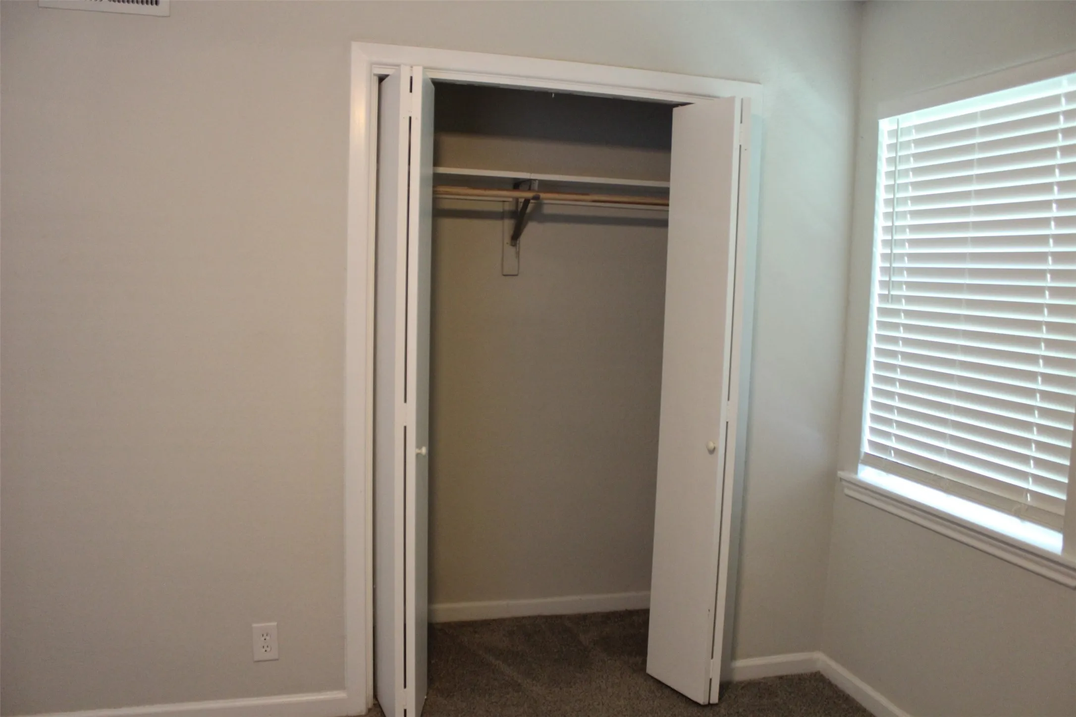 Neutral-toned bedroom featuring a bi-fold closet with an interior hanging rod and shelving