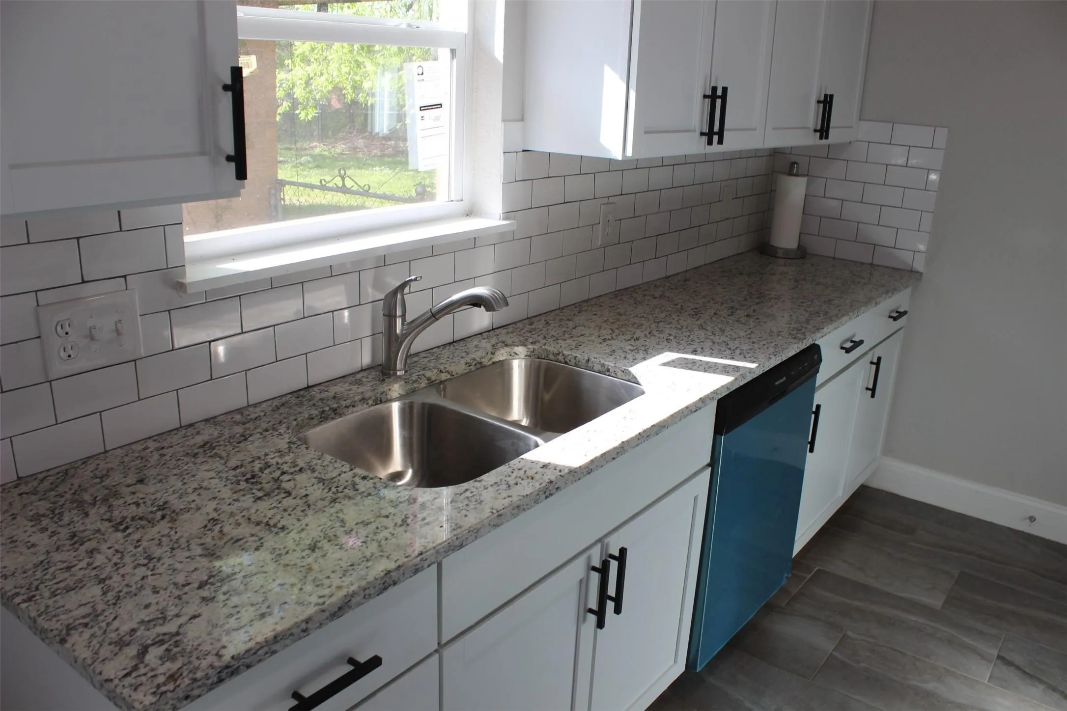Kitchen featuring white cabinetry, a double basin stainless steel sink, a modern faucet, and a subway tile backsplash