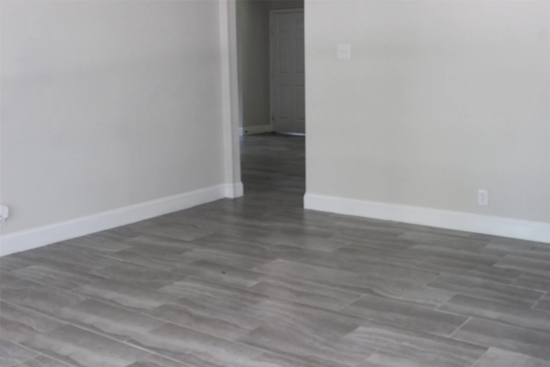 Light gray wood-look tile flooring throughout, complemented by white baseboards and neutral wall paint