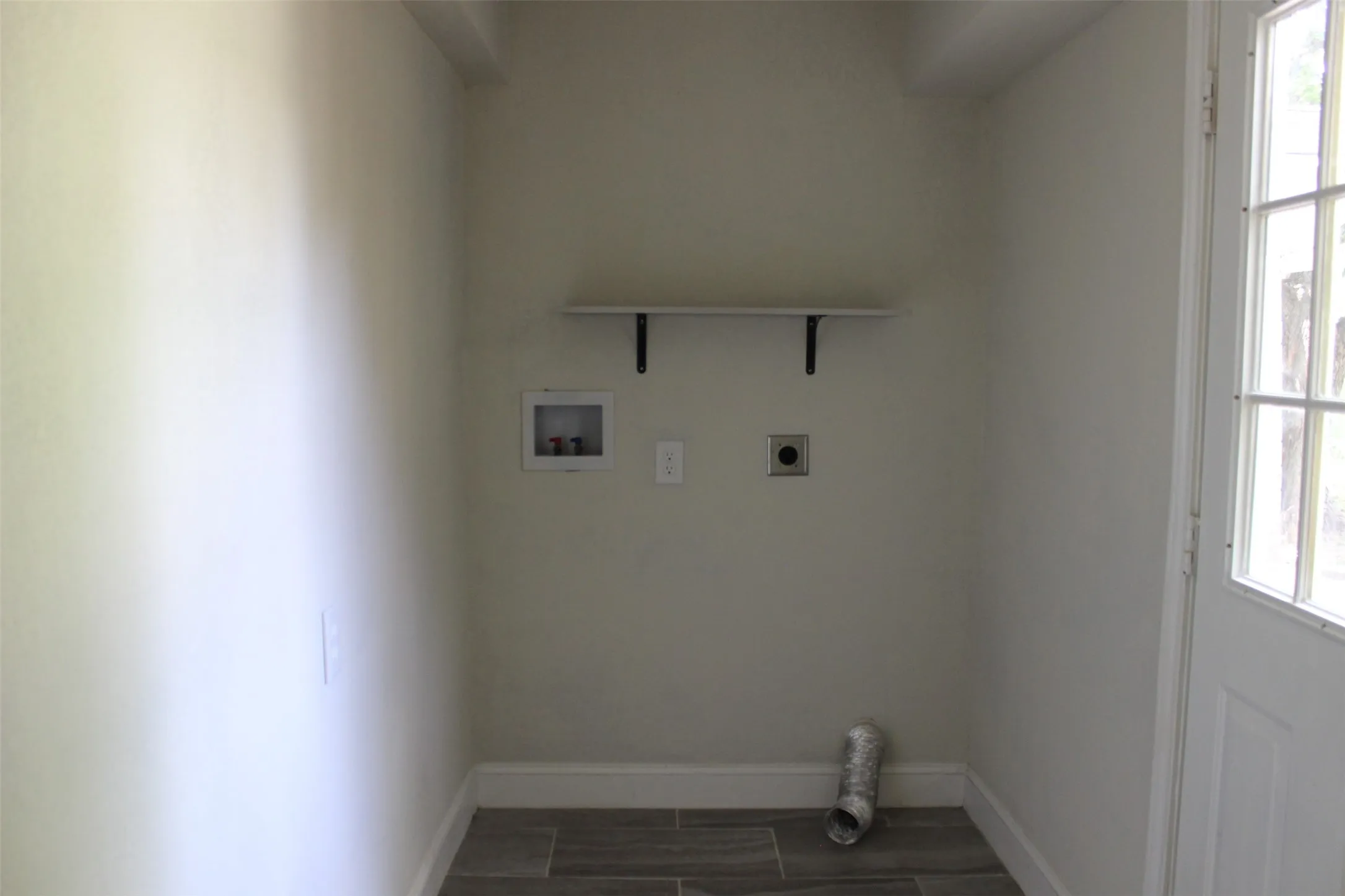 Dedicated utility space featuring a laundry hookup, dryer vent, and a wall-mounted shelf