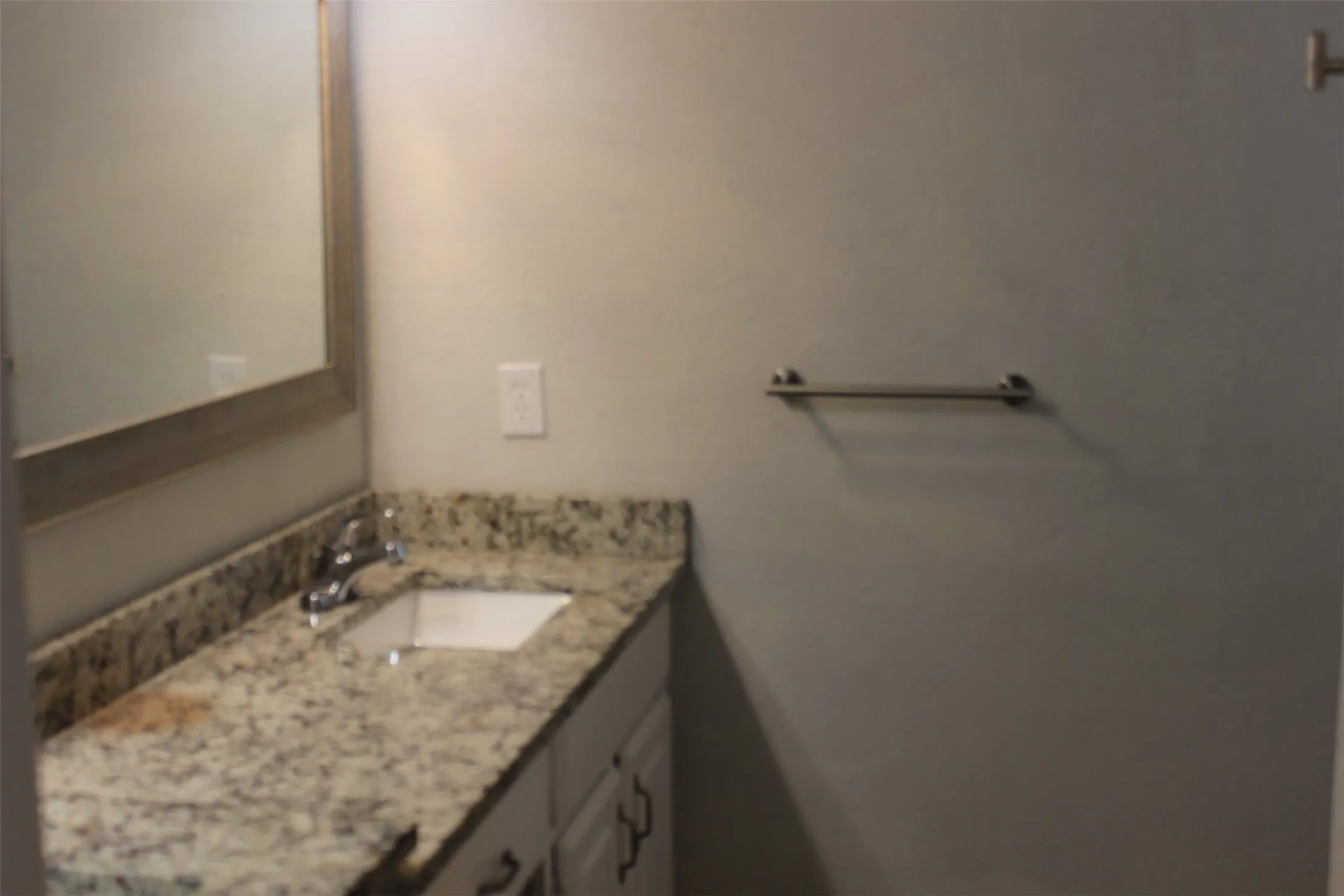 Vanity with a speckled countertop, undermount sink, and chrome faucet